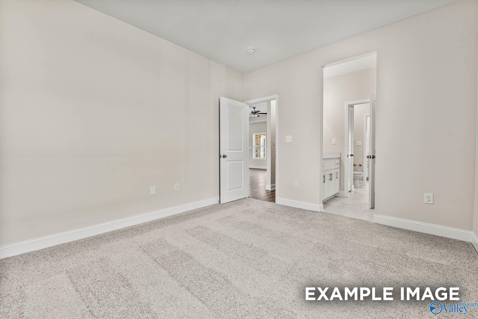 Bright bedroom with beige walls, plush carpet, open door to en-suite bath in Davidson Homes The Finleigh, Huntsville AL