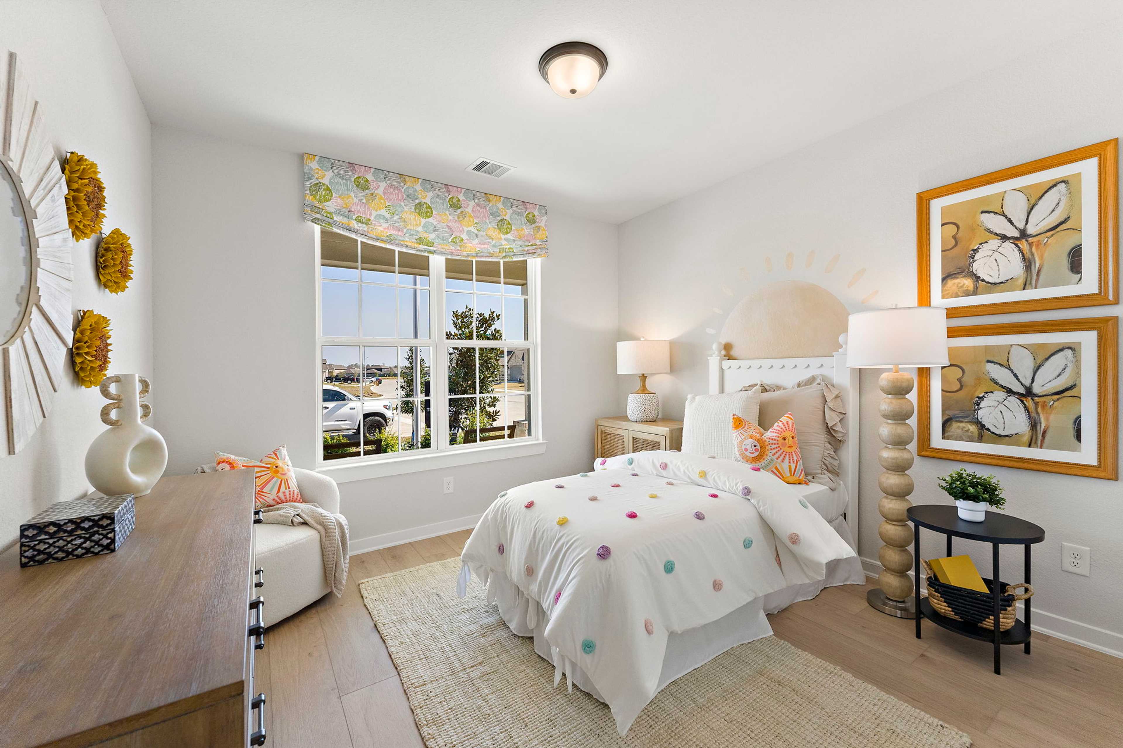 Cozy girl's bedroom at Sundance Cove in Crosby TX featuring white polka dot bedding, floral valance, sunburst decor, and hardwood floors