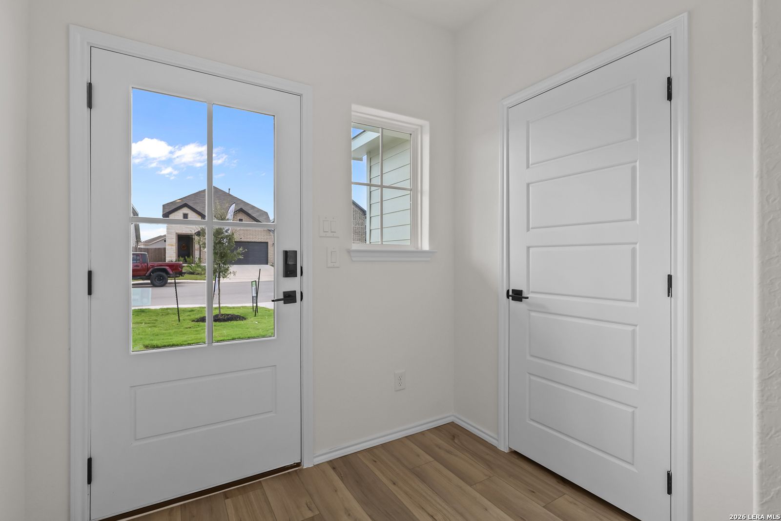 Bright entryway with glass-paneled front door and wood-look flooring in Davidson Homes The Summit B, Morgan Meadows, San Antonio