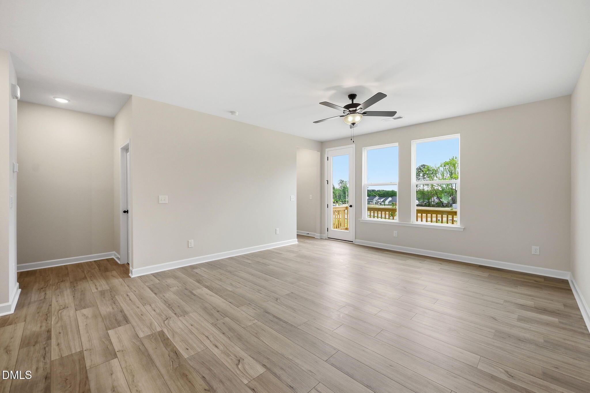 Spacious living room with wood-style flooring and ceiling fan in The Mitchell floor plan at Camden Park, Knightdale, NC.
