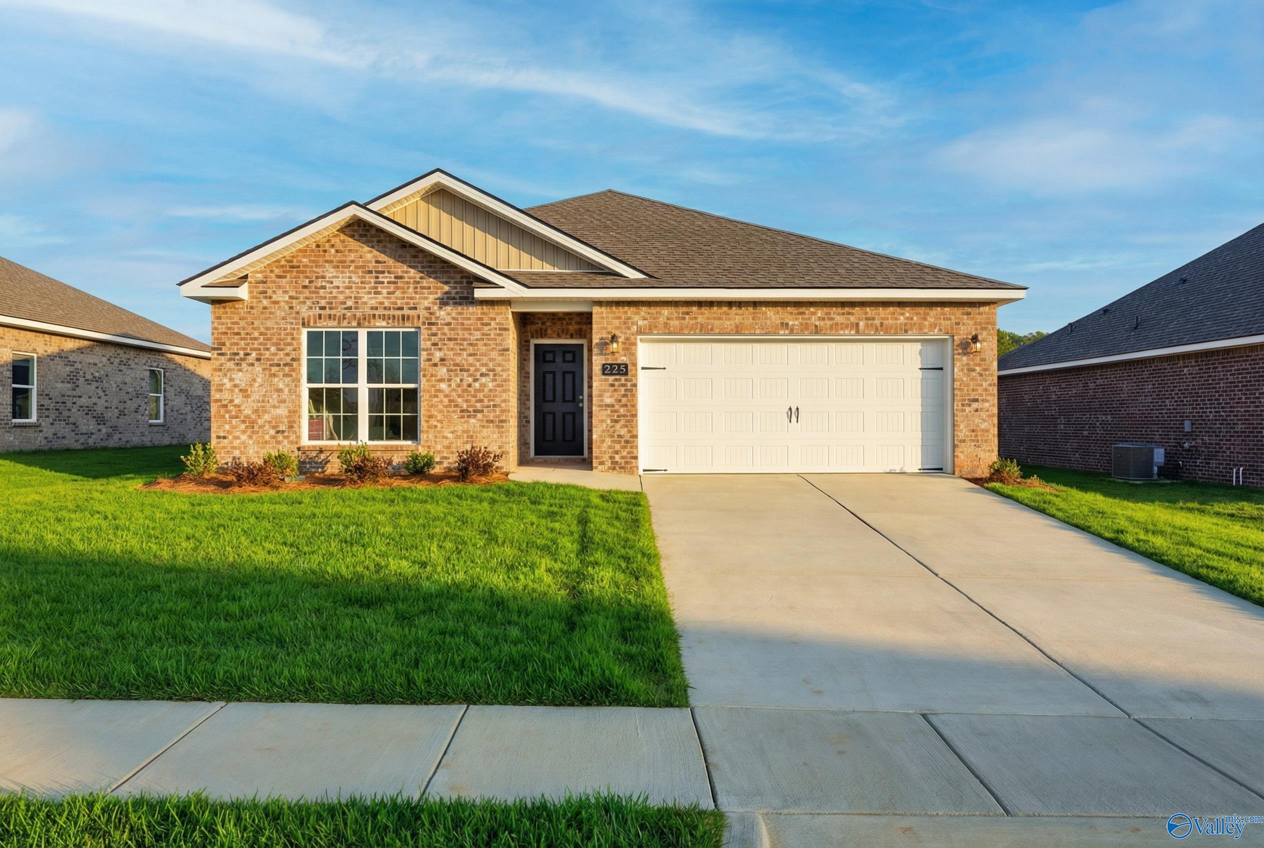 Modern single-story brick home with 2-car garage, driveway, and lush green lawn in Wood Trail, Toney, Alabama - Davidson Homes The Asheville