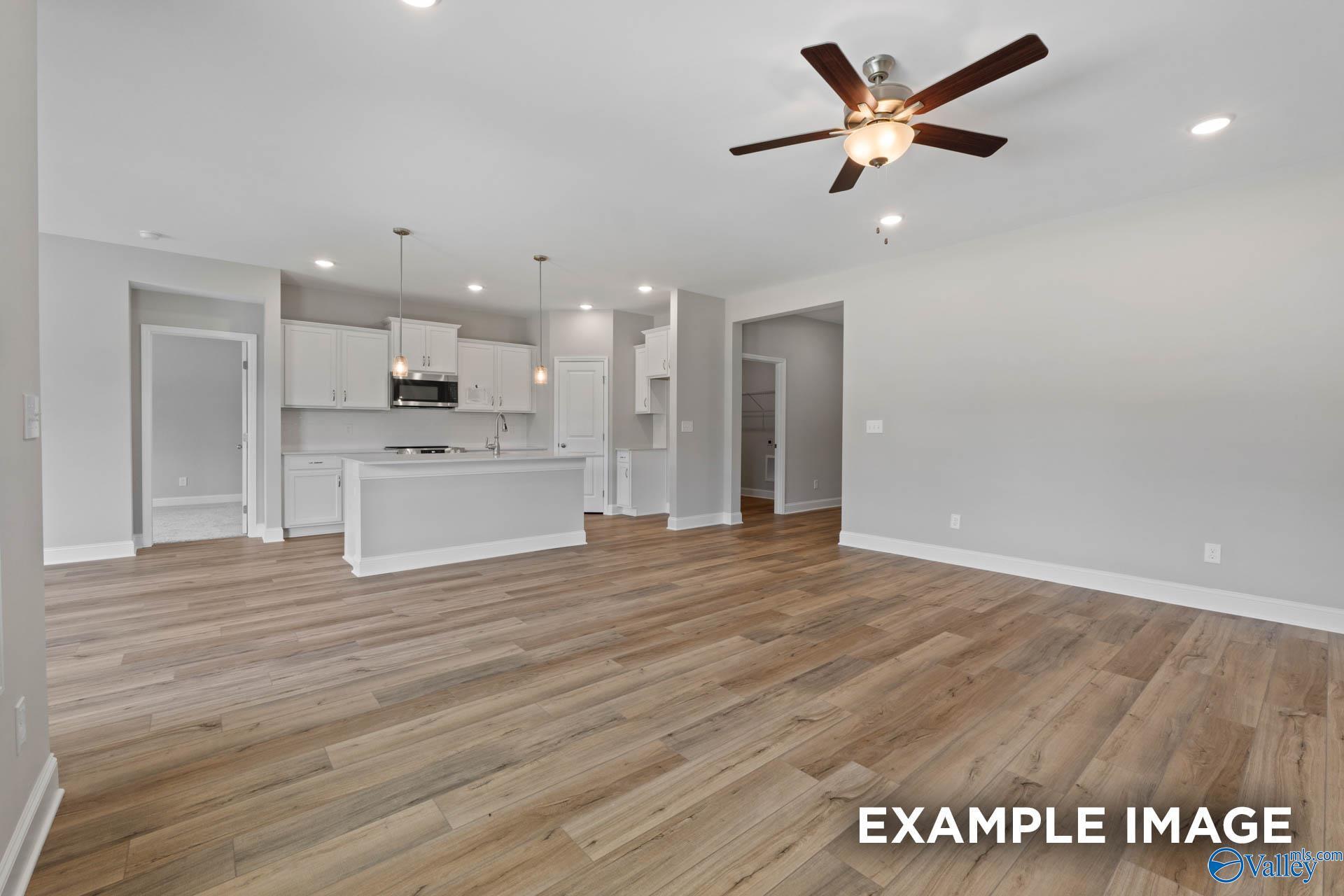 Open-concept kitchen with white cabinets, center island, ceiling fan, and hardwood floors in Davidson Homes The Everett B, Huntsville AL
