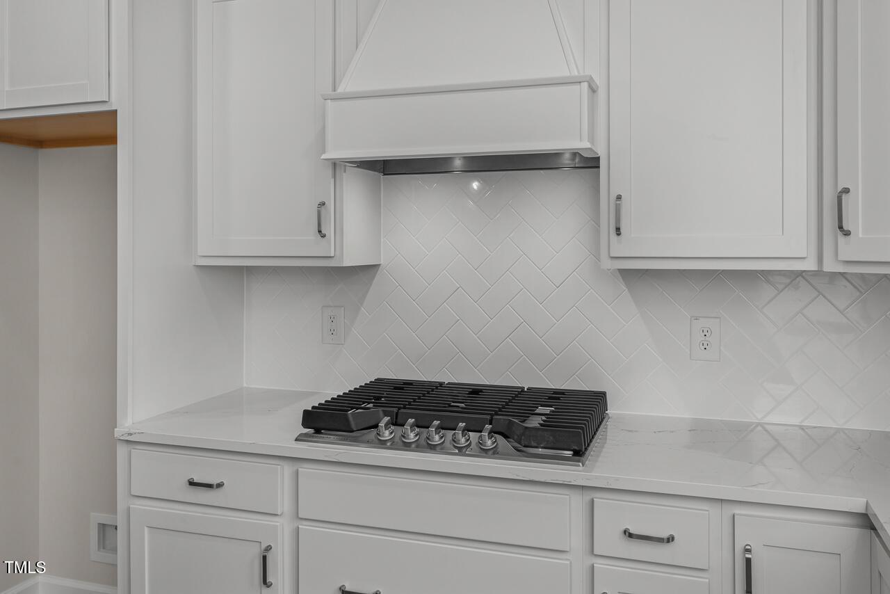 Modern white kitchen with shaker cabinets, herringbone subway tile backsplash, gas range in Davidson Homes The Aspen B, Wake Forest, NC