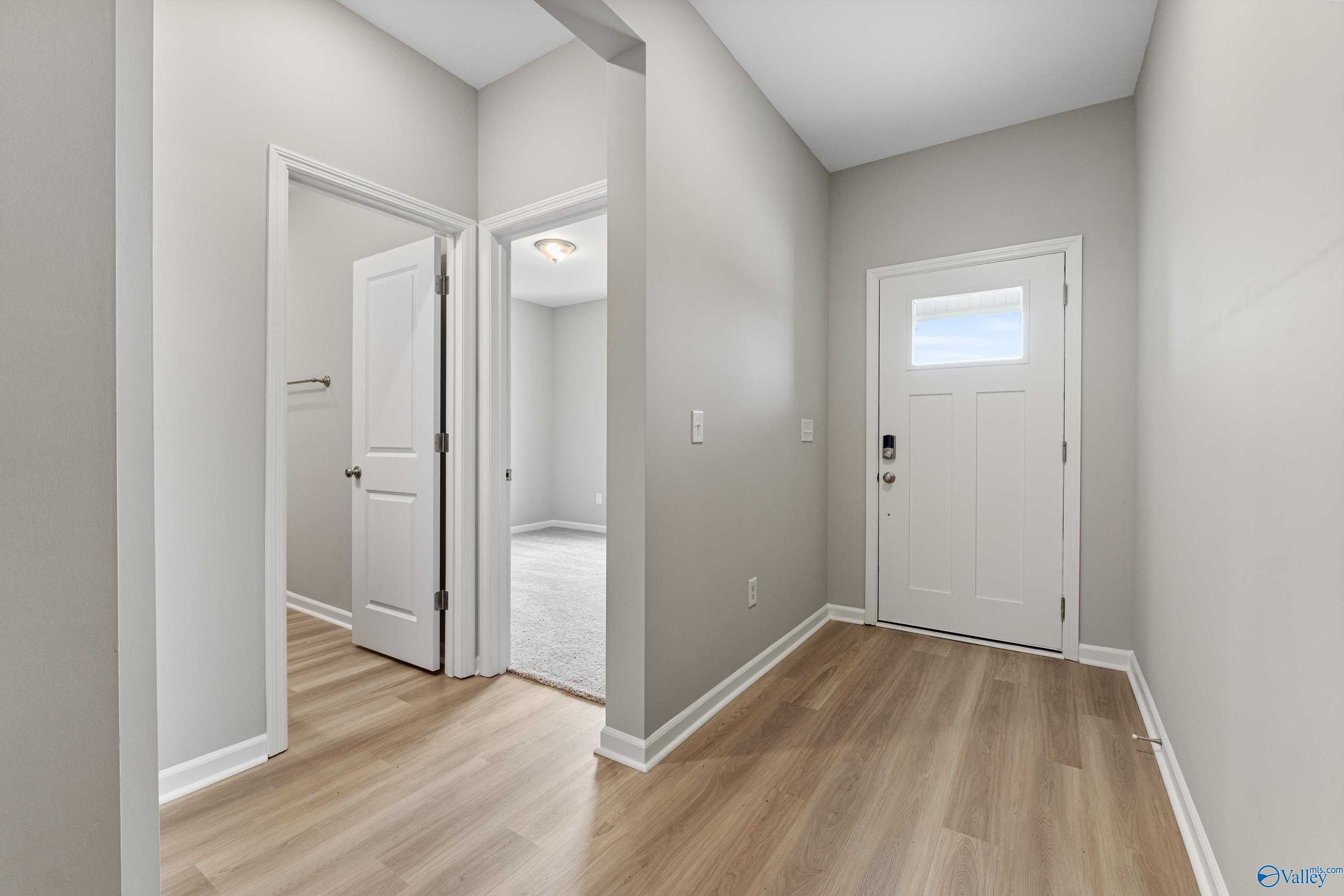 Bright entry hallway with white doors, neutral gray walls, and luxury vinyl plank floors in The Aurora 4-bedroom home, Fayetteville, TN