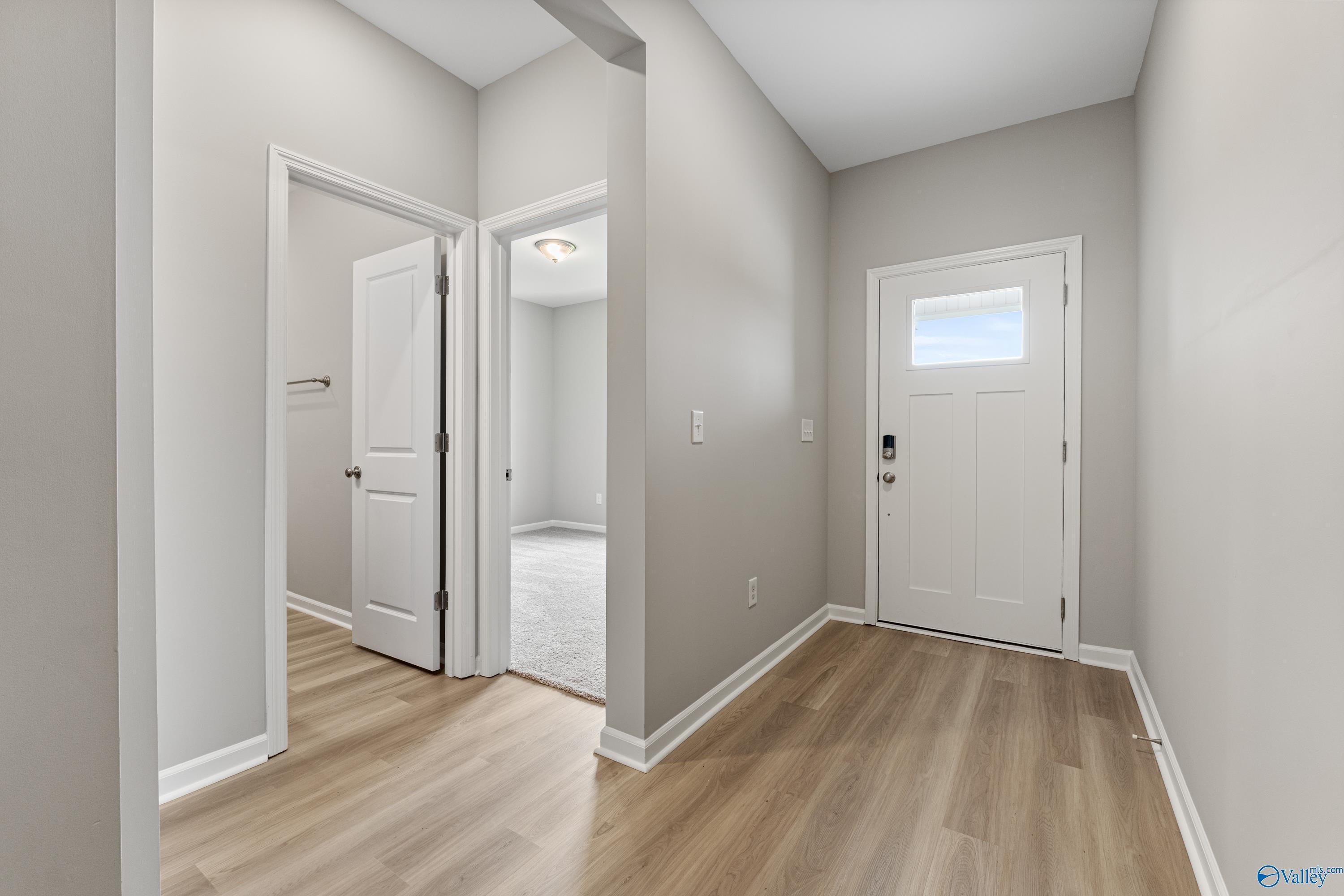 Bright entryway hallway with light wood floors, white doors, and neutral walls in Davidson Homes The Aurora, Fayetteville, TN