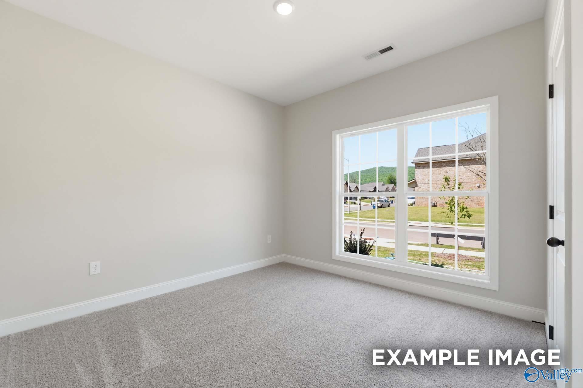 Bright secondary bedroom with neutral walls and plush carpet in The Franklin C floor plan at The Meadows, Athens, AL.