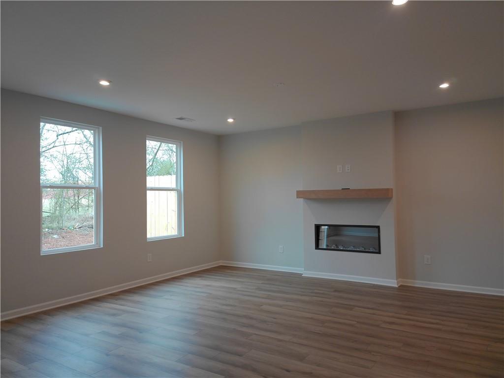 Cozy living room featuring gas fireplace, hardwood floors, and large windows in Davidson Homes The Cary A, Winder, Georgia