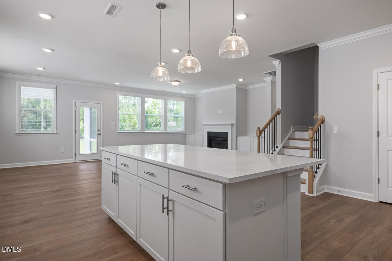 Open-concept kitchen with large island and pendant lighting in The Ashport L floor plan at Sage on North Main, Wake Forest.