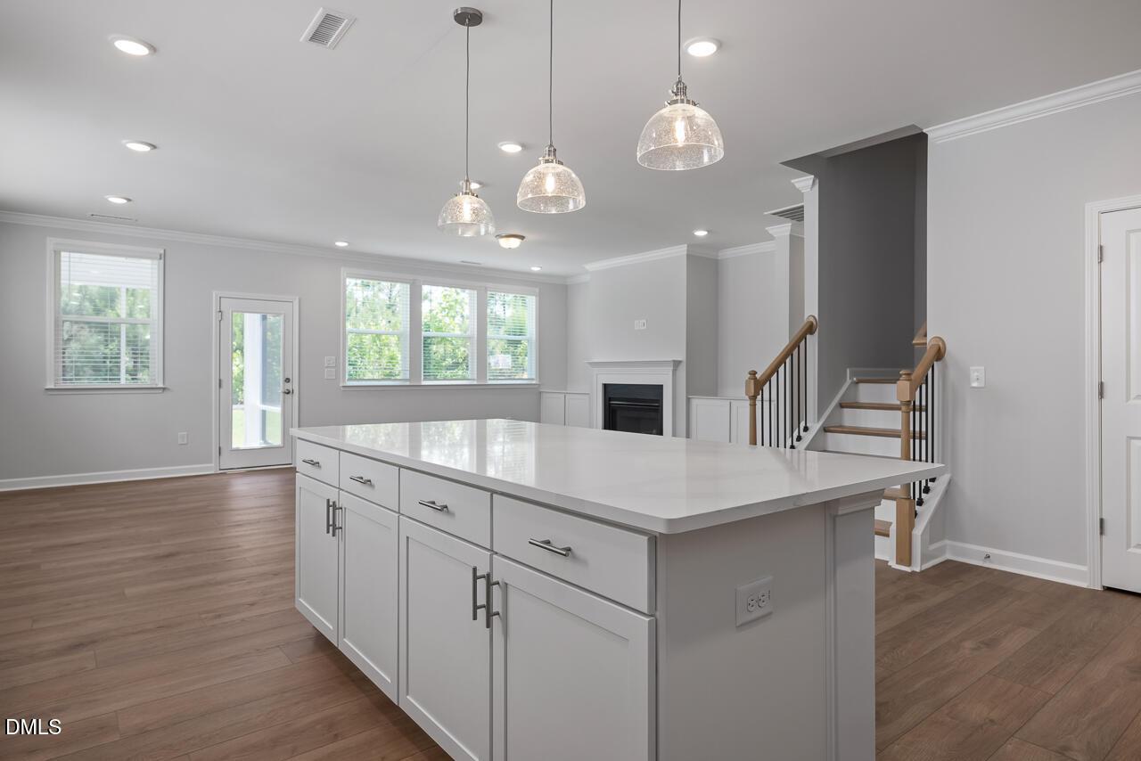 Open-concept kitchen with large island and pendant lighting in The Ashport L floor plan at Sage on North Main, Wake Forest.