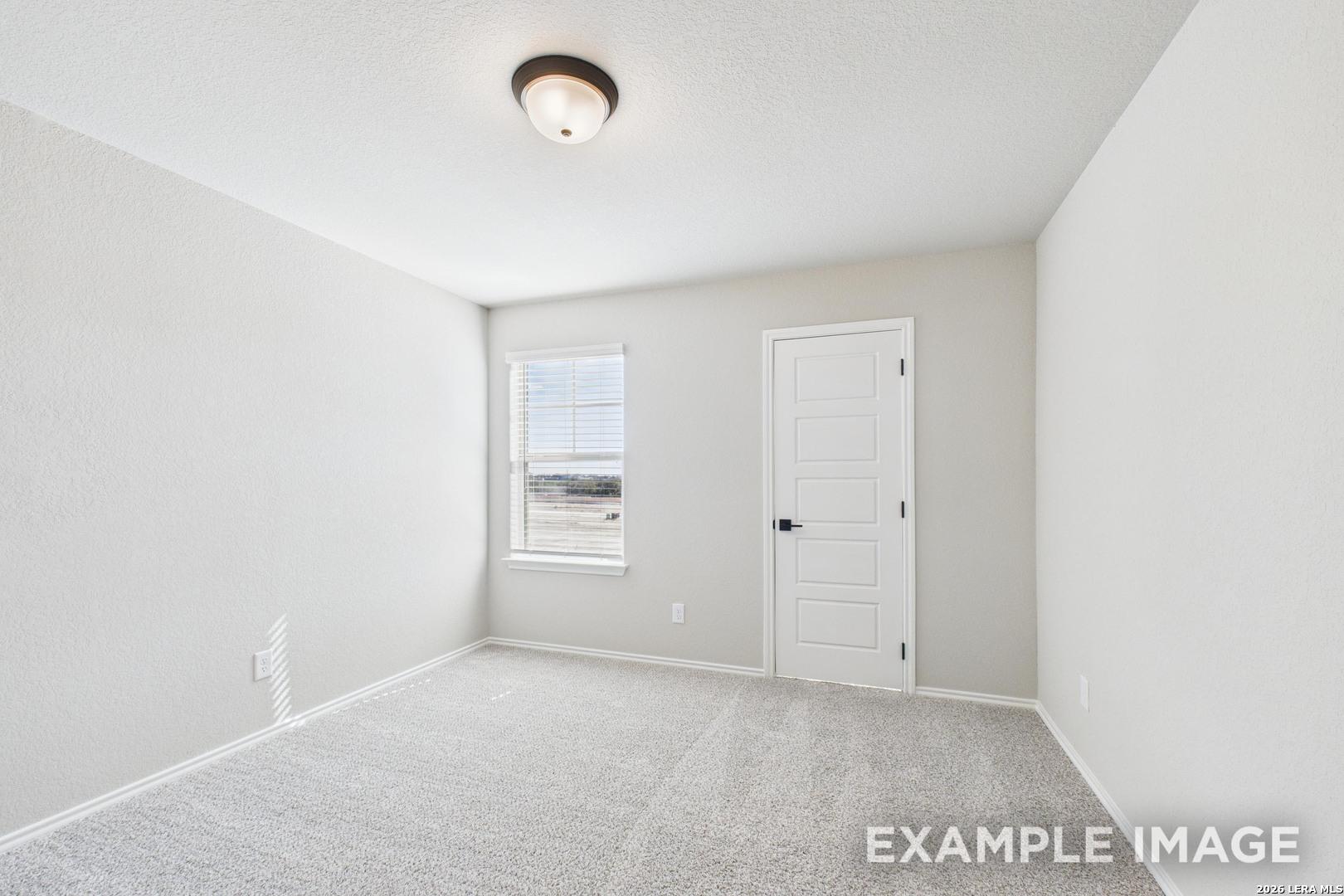 Bright, carpeted bedroom with neutral walls in The Charlotte B floor plan by Davidson Homes in Cedar Heights, San Antonio.