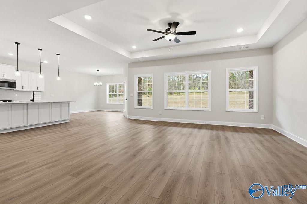 Open-concept living room with kitchen island, hardwood floors, and large windows in The Rockford B by Davidson Homes, Hartselle, AL