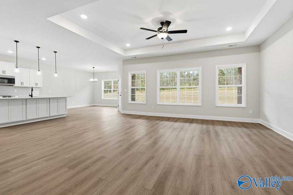 Open-concept living room with kitchen island, hardwood floors, and large windows in The Rockford B by Davidson Homes, Hartselle, AL