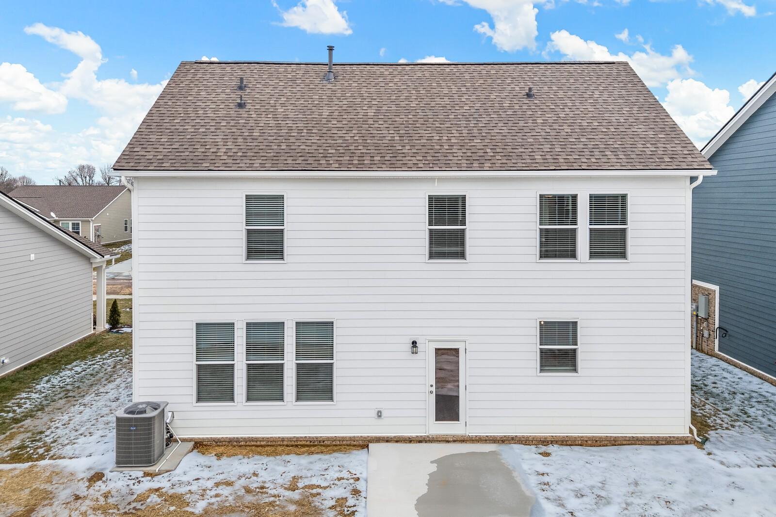 Rear view of two-story white home with windows, back door, and AC unit in snowy yard, Sage Farms, White House, TN