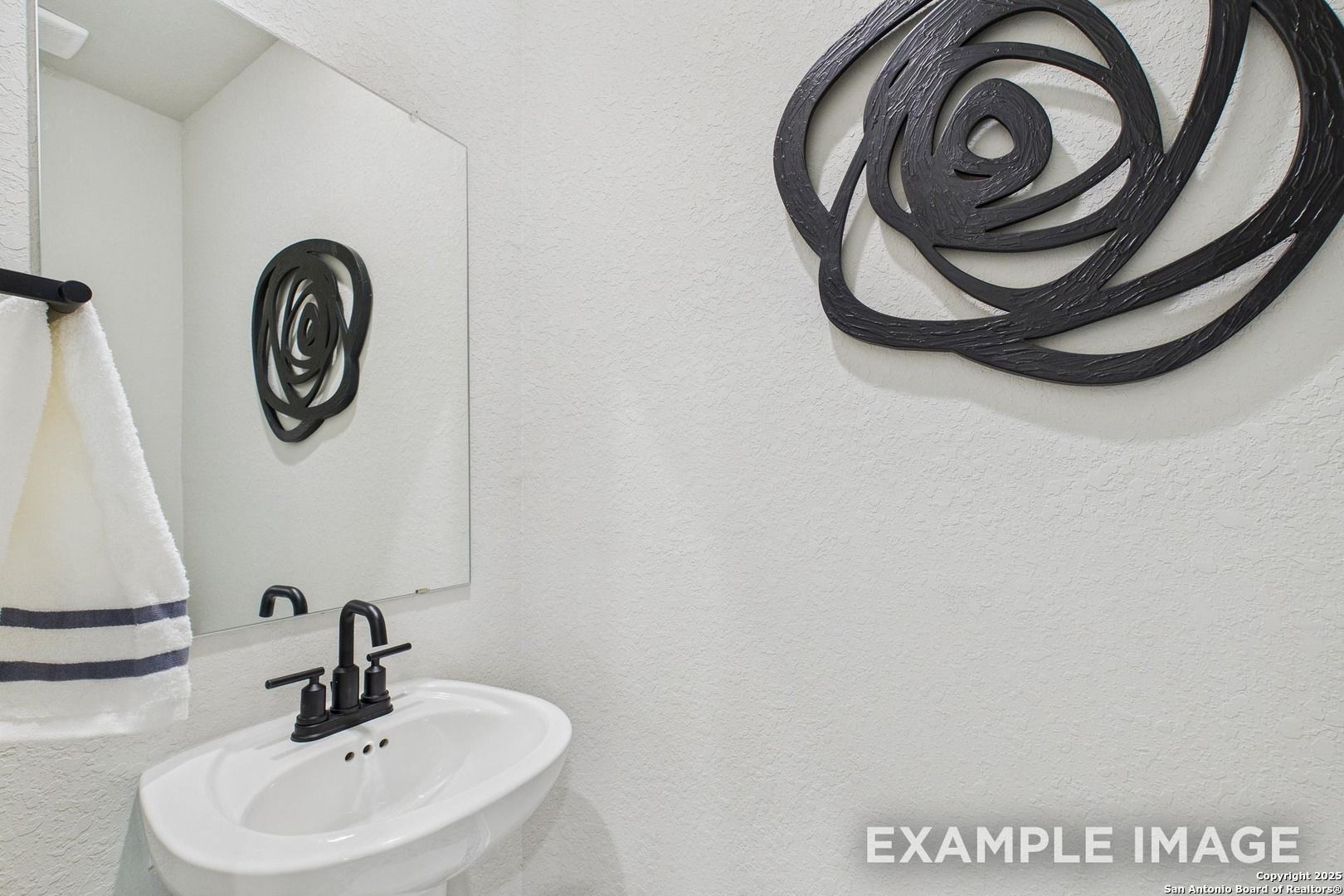 Modern powder room featuring white vanity, black faucet, towel bar, and black rose wall art in Davidson Homes The Charlotte A, San Antonio