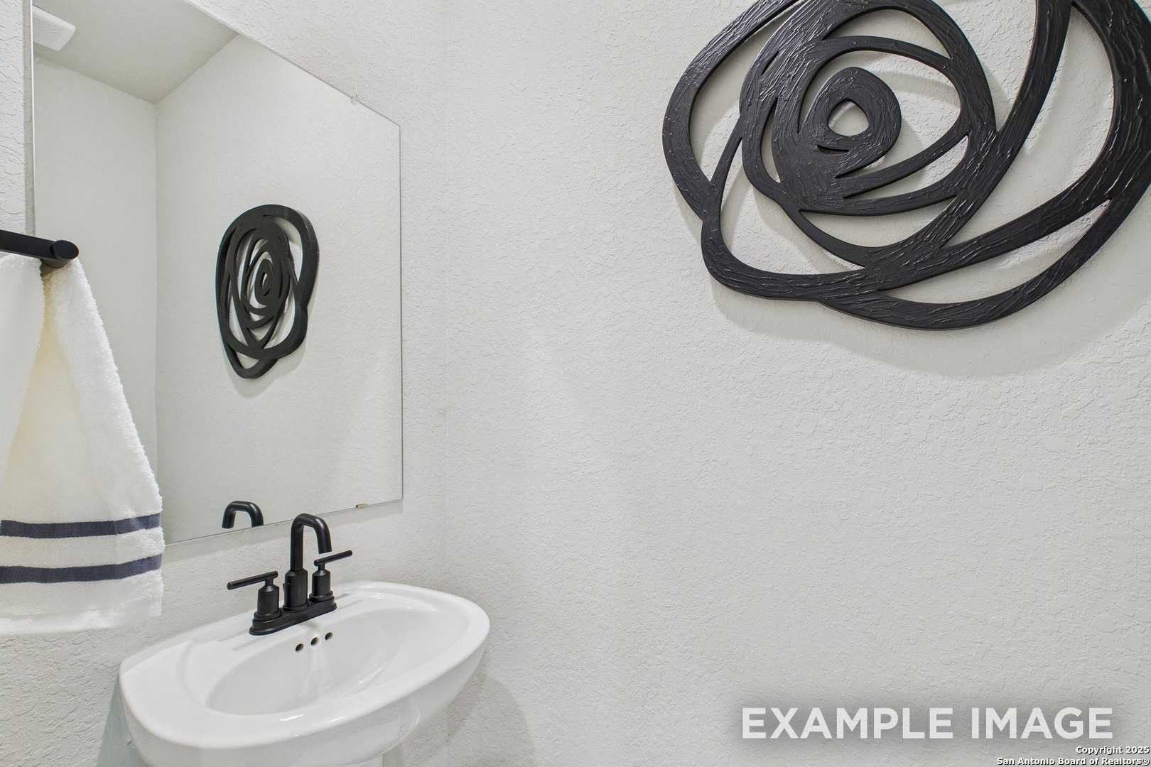 Modern powder room featuring white vanity, black faucet, towel bar, and black rose wall art in Davidson Homes The Charlotte A, San Antonio