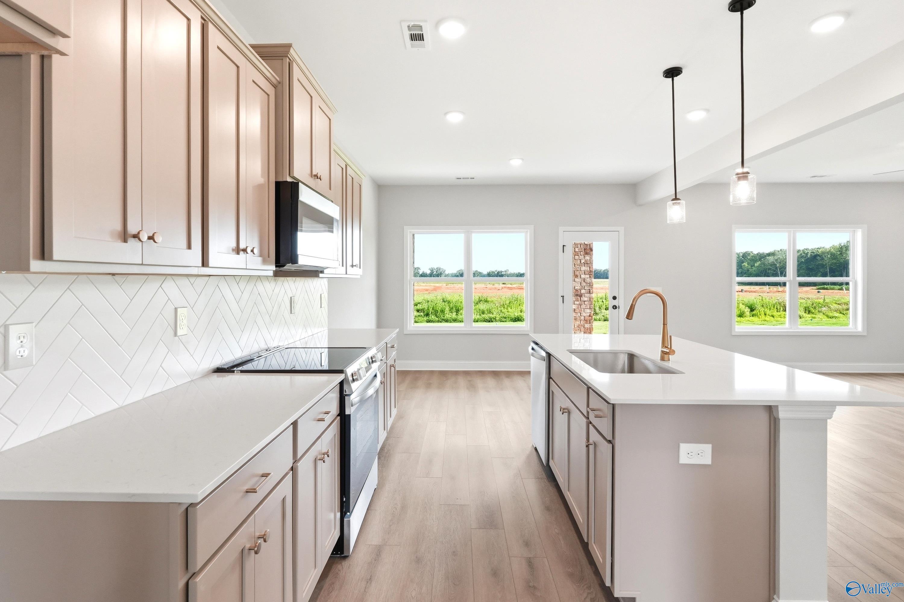 Modern kitchen with quartz countertops and herringbone backsplash in The Shelby A floor plan at Clearview, Hazel Green, AL.