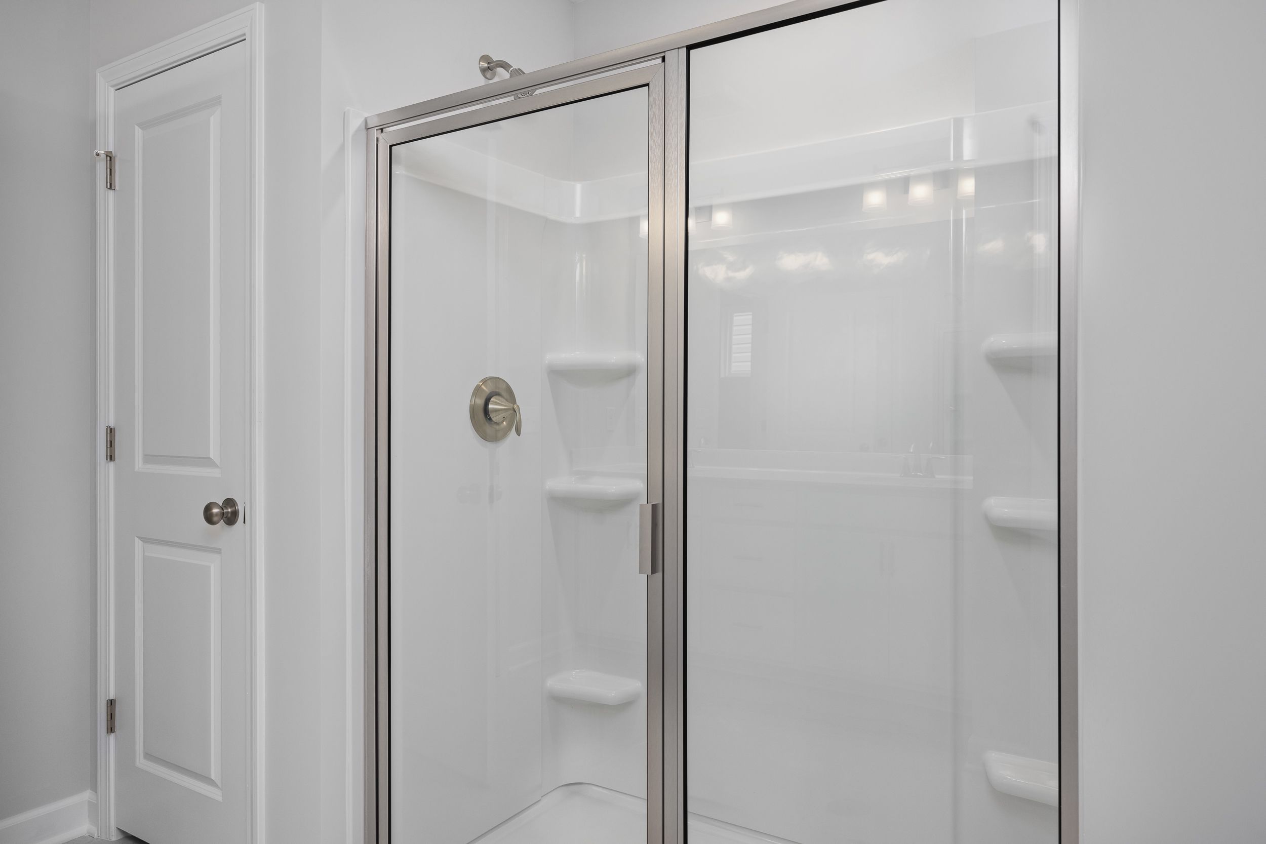 Modern walk-in shower with glass doors and built-in shelving in the master suite of The Durham by Davidson Homes.