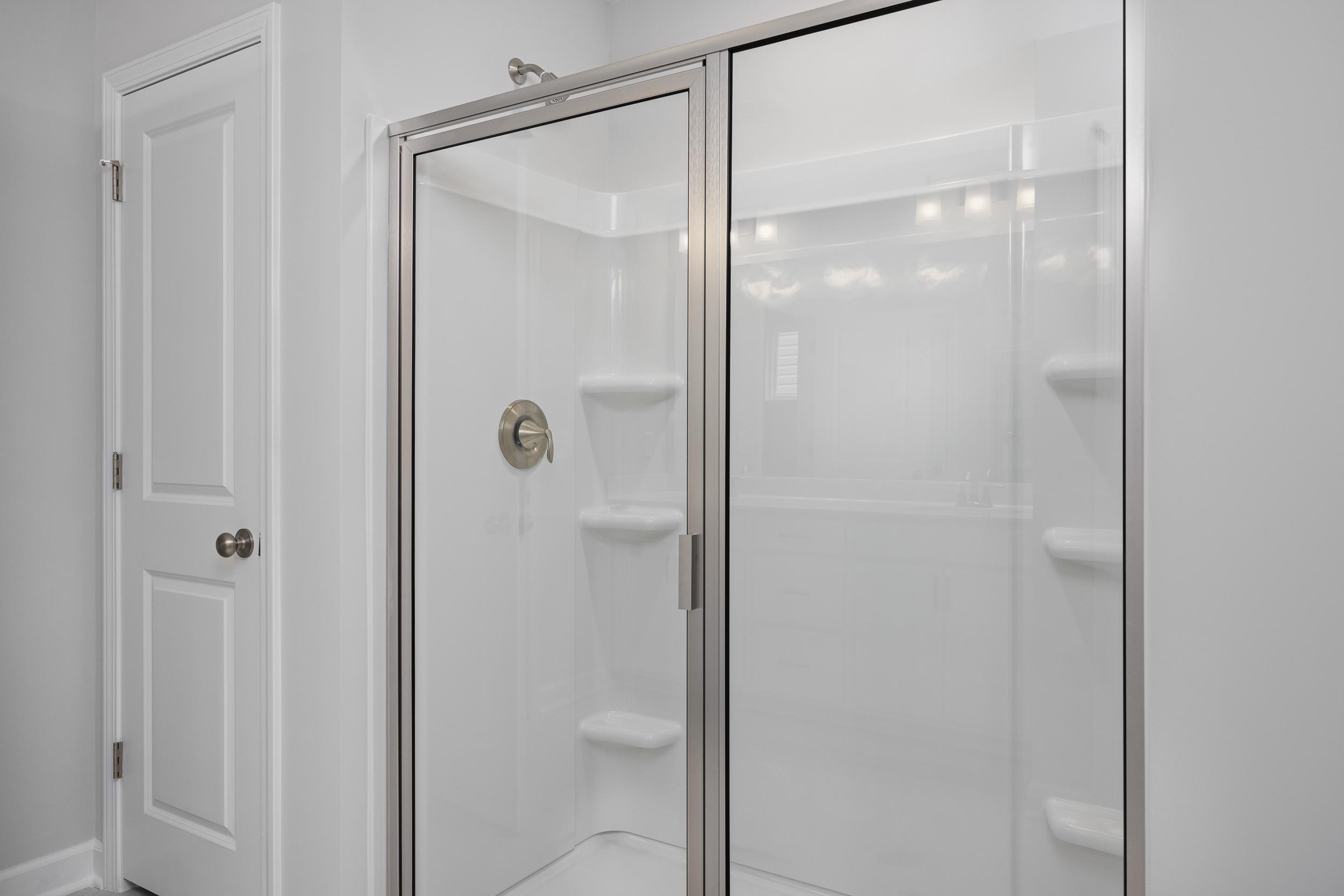 Modern walk-in shower with glass doors and built-in shelving in the master suite of The Durham by Davidson Homes.