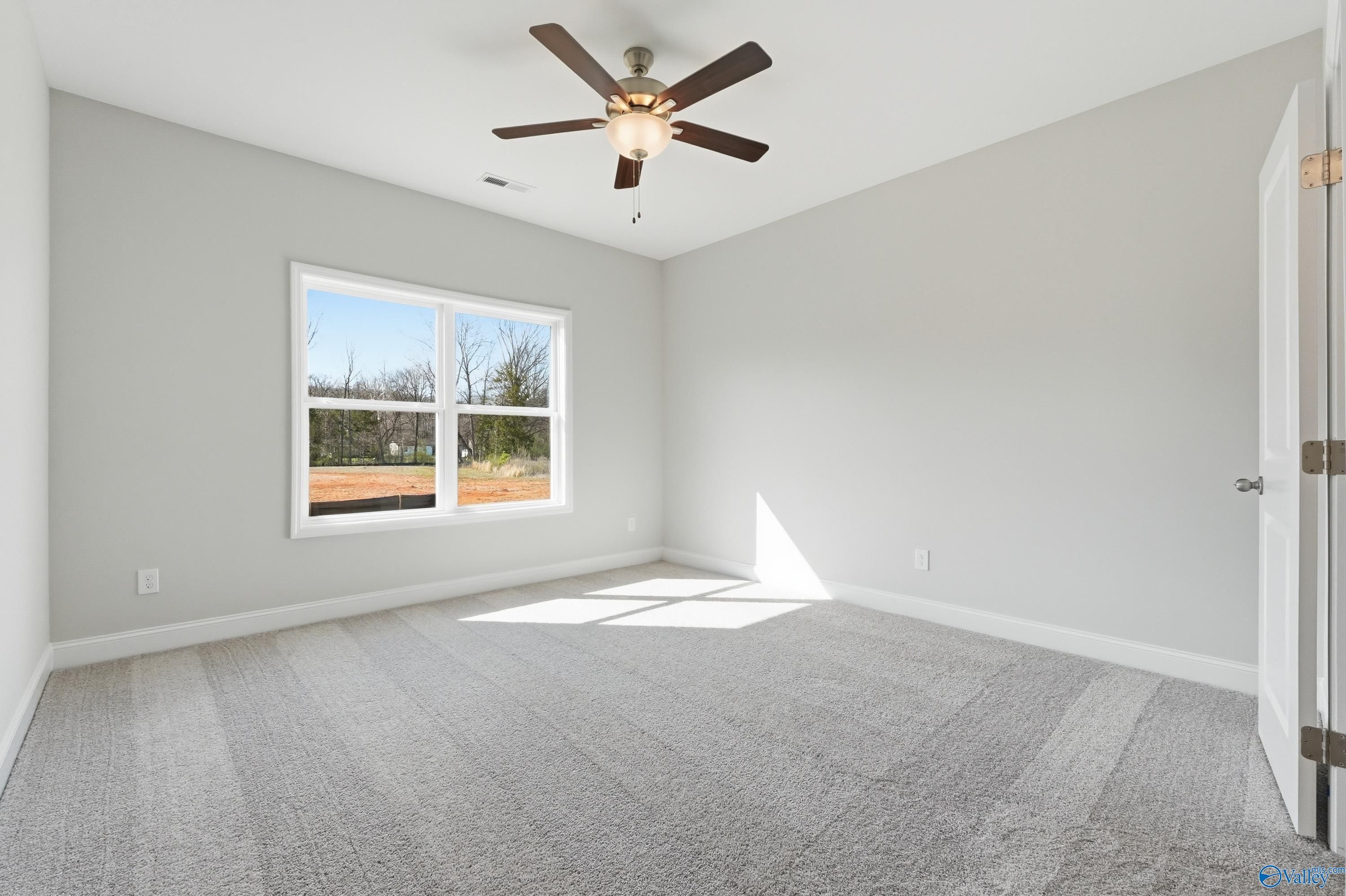 Bright secondary bedroom with gray walls, ceiling fan, and large window in Davidson Homes The Asheville C, Huntsville AL