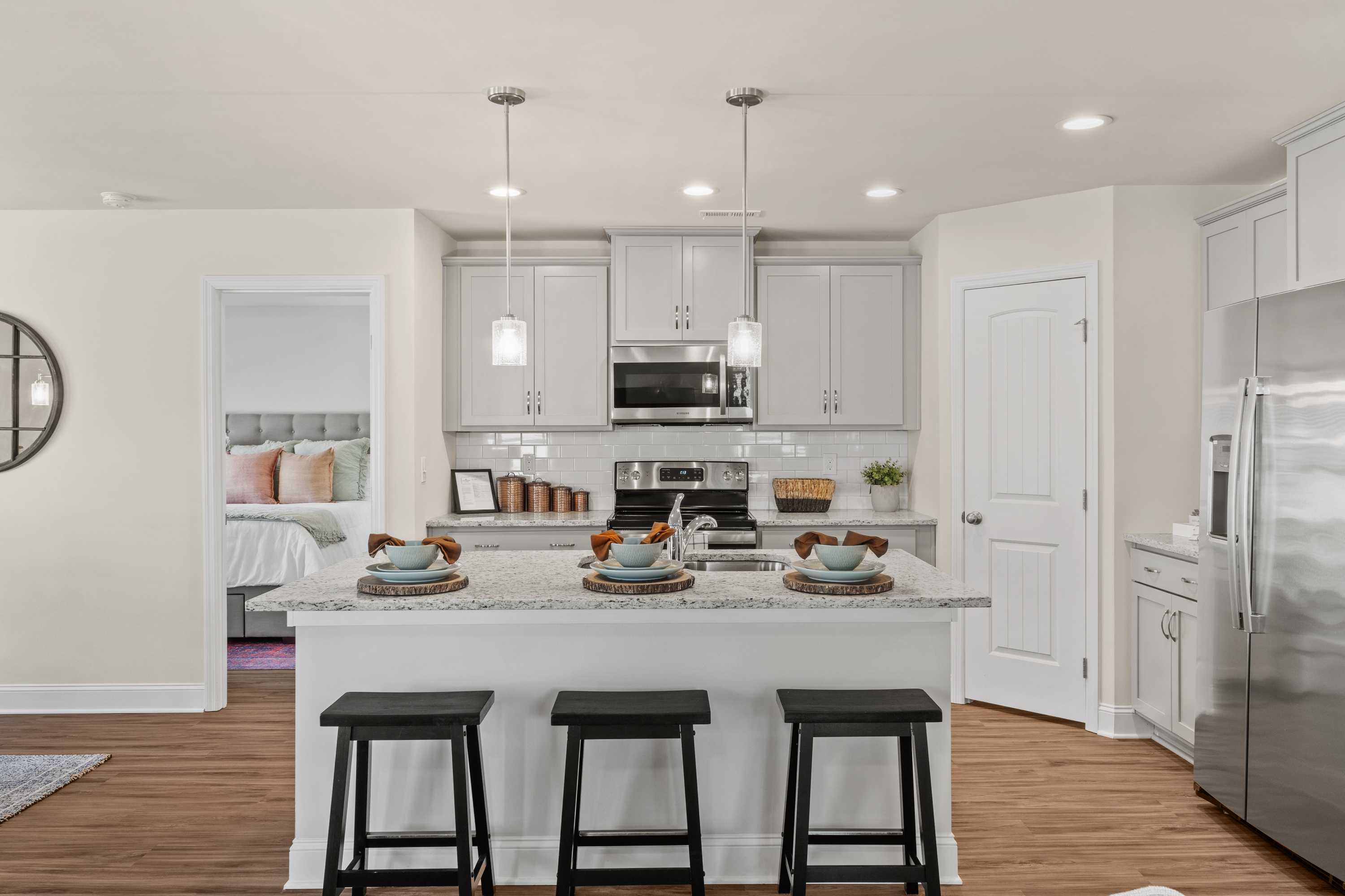 Spacious white kitchen at Berry Cove in New Market Alabama with island seating, stainless appliances, hardwood floors