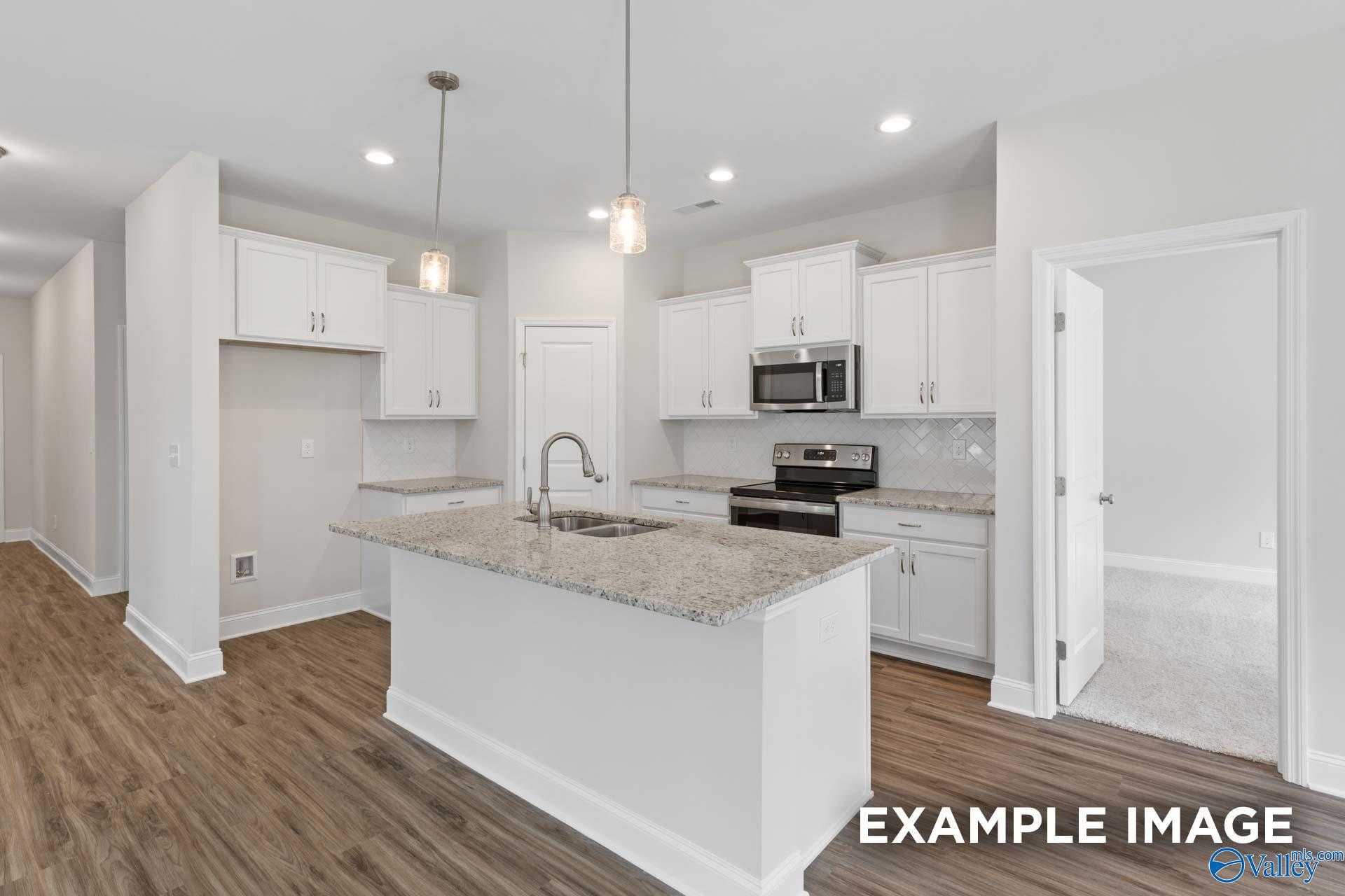 Modern kitchen featuring white cabinets, granite island, stainless steel appliances in The Franklin by Davidson Homes, Meridianville, AL