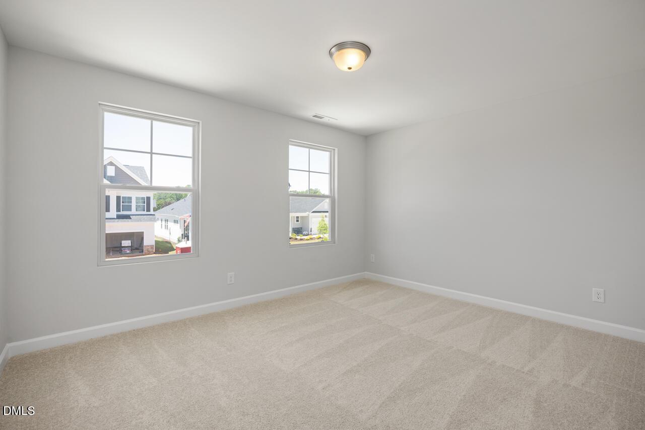 Bright neutral bedroom with plush carpeting in The Adalynn A floor plan at Gregory Village in Lillington, North Carolina.
