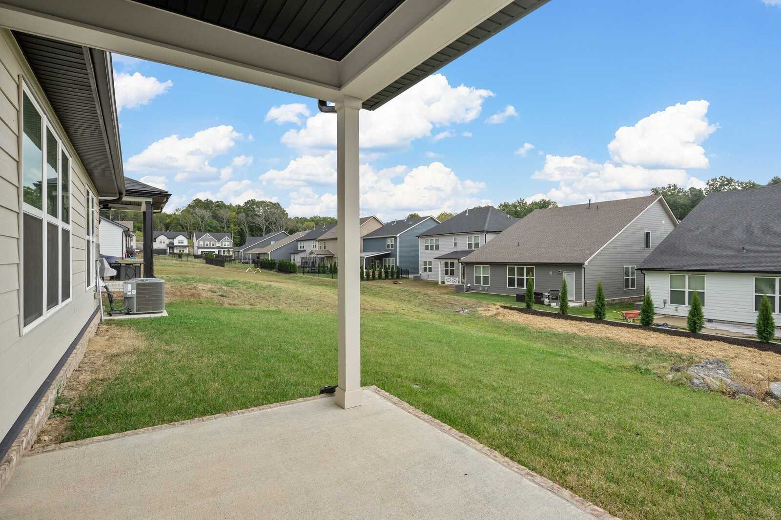 Covered back patio with sturdy beams overlooking lush green yard and neighboring homes in Carellton, Gallatin, Tennessee