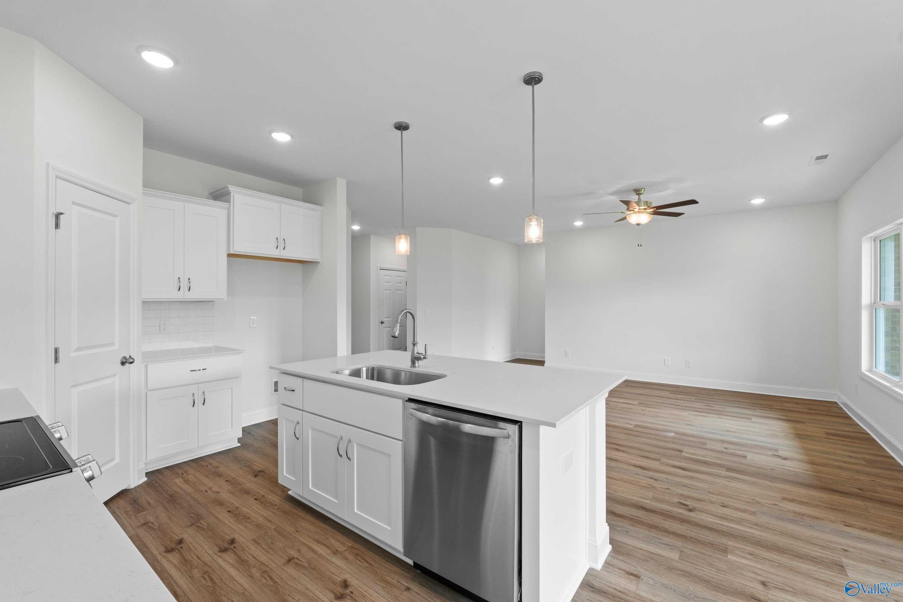 Modern white kitchen with center island sink, stainless dishwasher, open to family room with ceiling fan in Davidson Homes The Asheville C, Athens AL