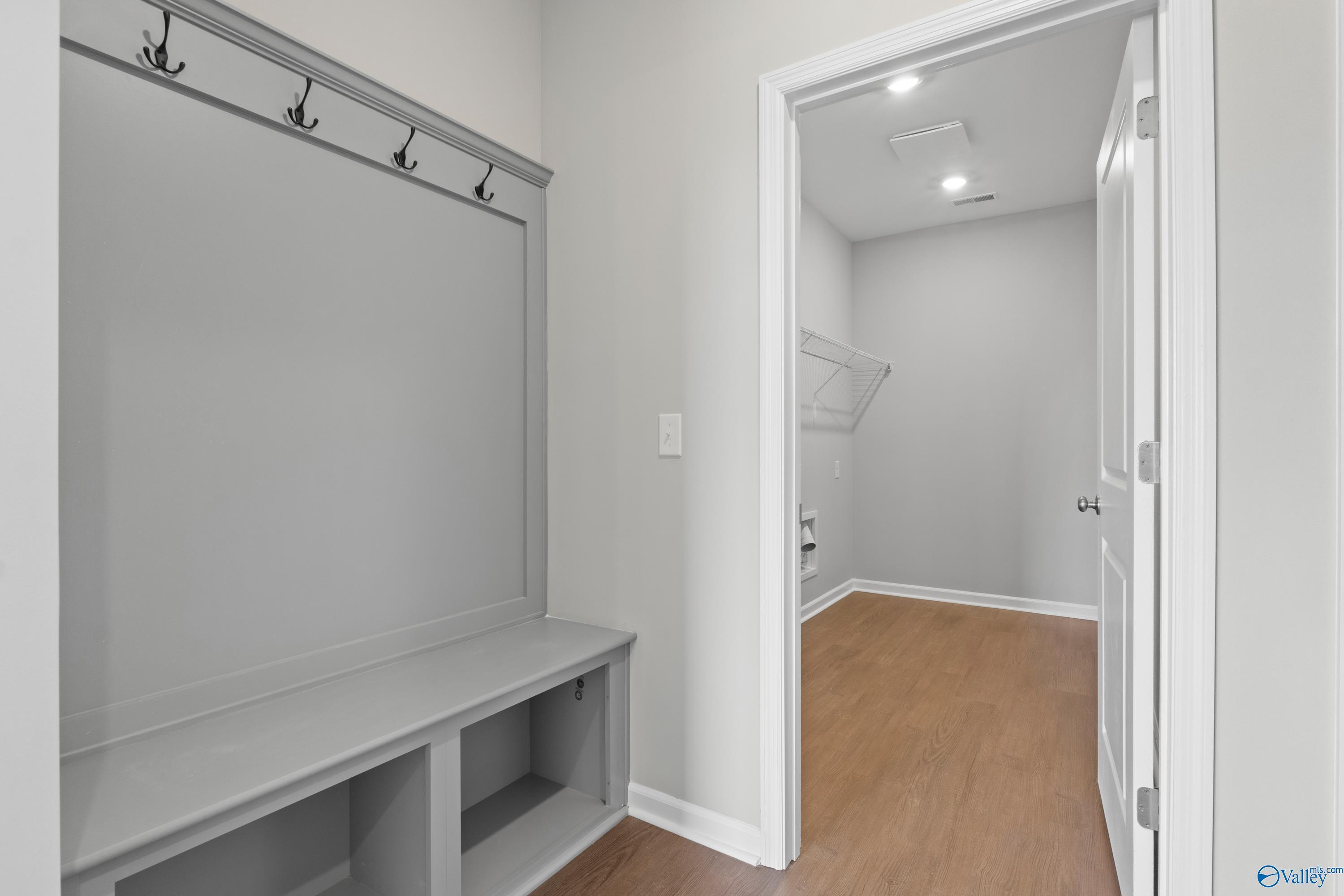 Functional mudroom with gray walls, built-in bench, coat hooks, and laundry area in Davidson Homes The Dorado, Athens, Alabama