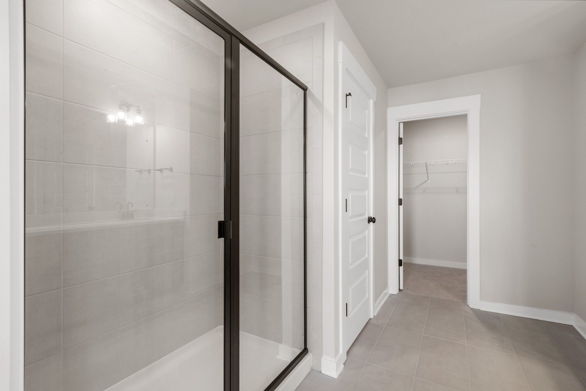 Modern frameless glass shower with subway tile and adjacent walk-in closet in master bath, Davidson Homes The Willow B, White House, TN