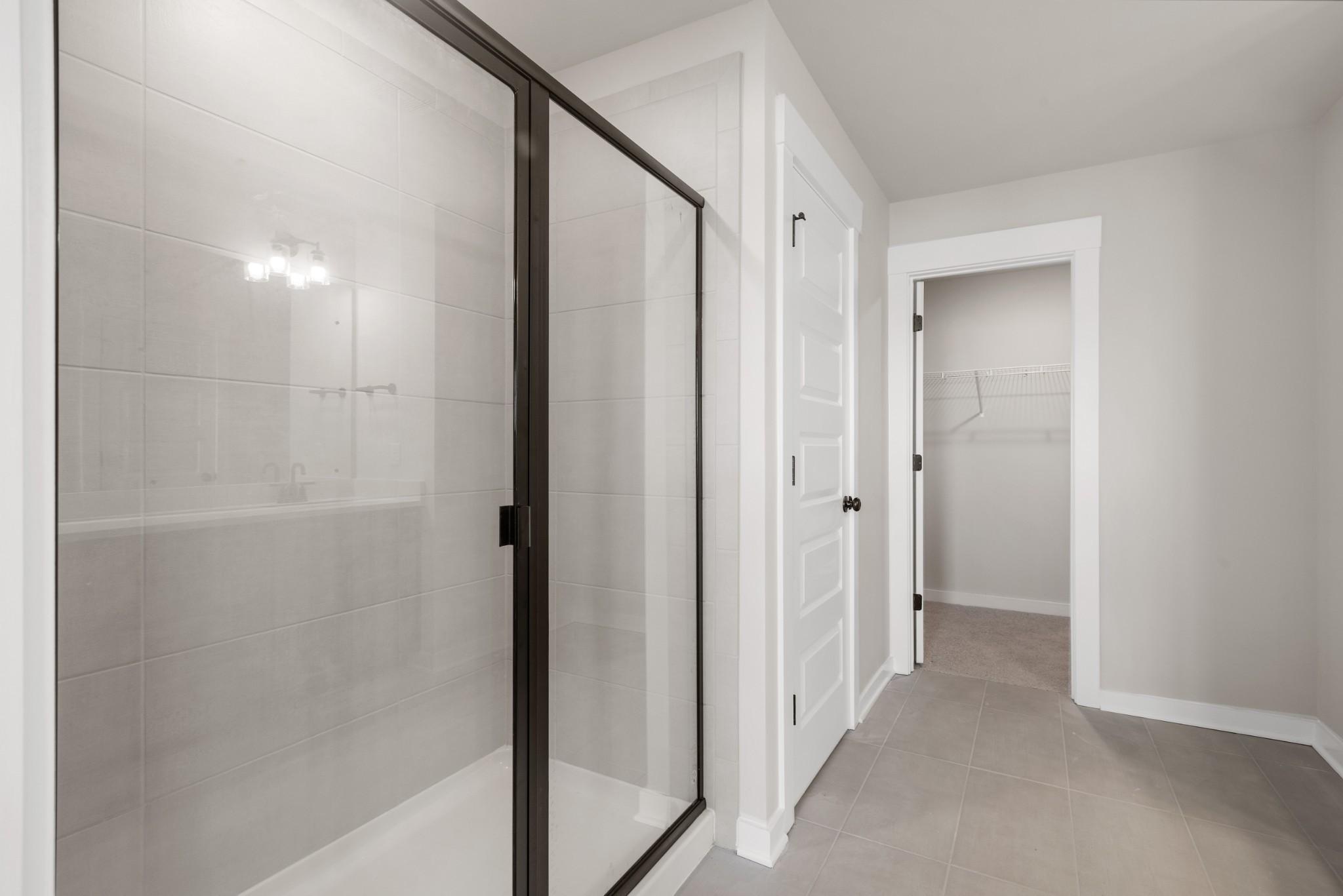 Modern frameless glass shower with subway tile and adjacent walk-in closet in master bath, Davidson Homes The Willow B, White House, TN