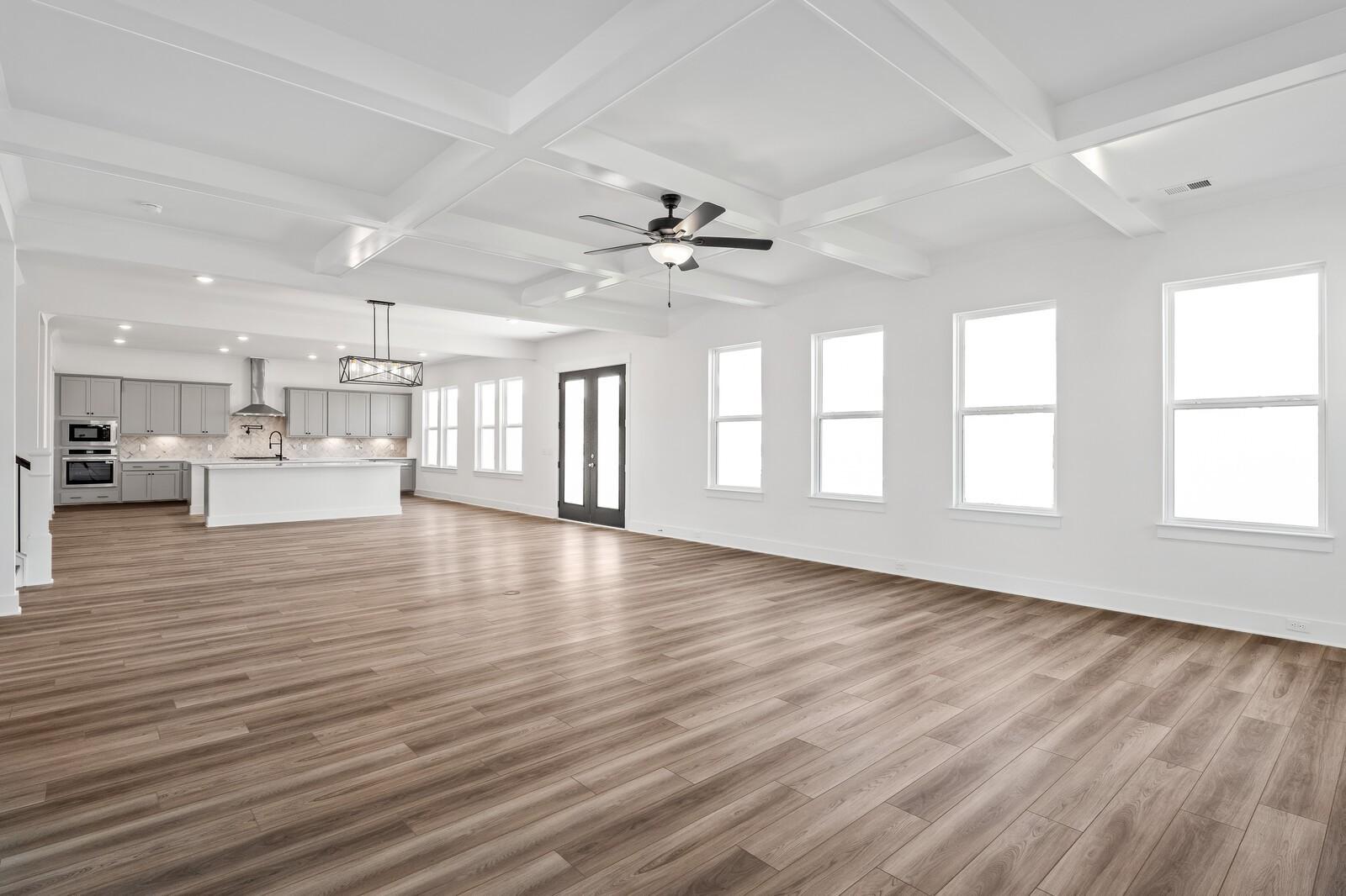 Open-concept living and kitchen with gray cabinets, white island, coffered ceiling, and large windows in The Alston A, Murfreesboro, TN