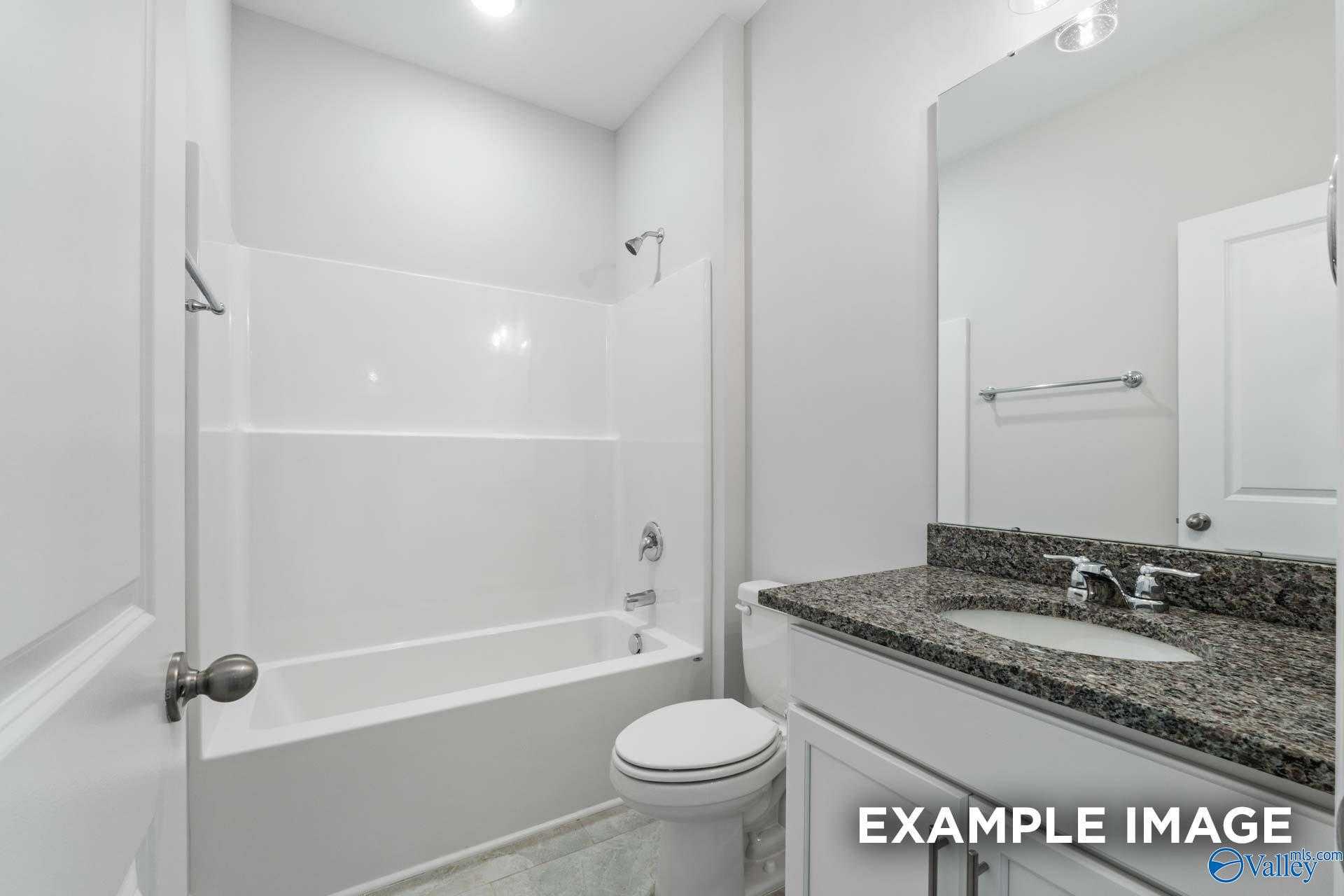 Modern bathroom featuring tub-shower combo, granite countertop vanity, and white tiles in Davidson Homes The Lanier, Meridianville, Alabama