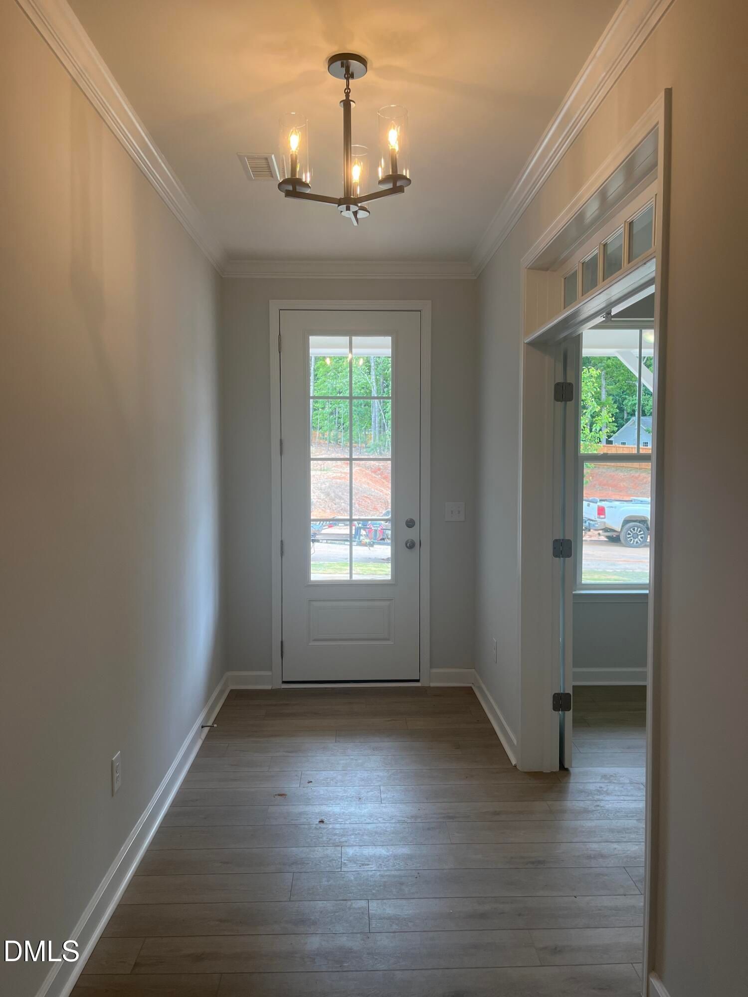 Bright entryway with hardwood floors, chandelier, and glass-paneled door in Davidson Homes The Birch II E, Wake Forest, NC