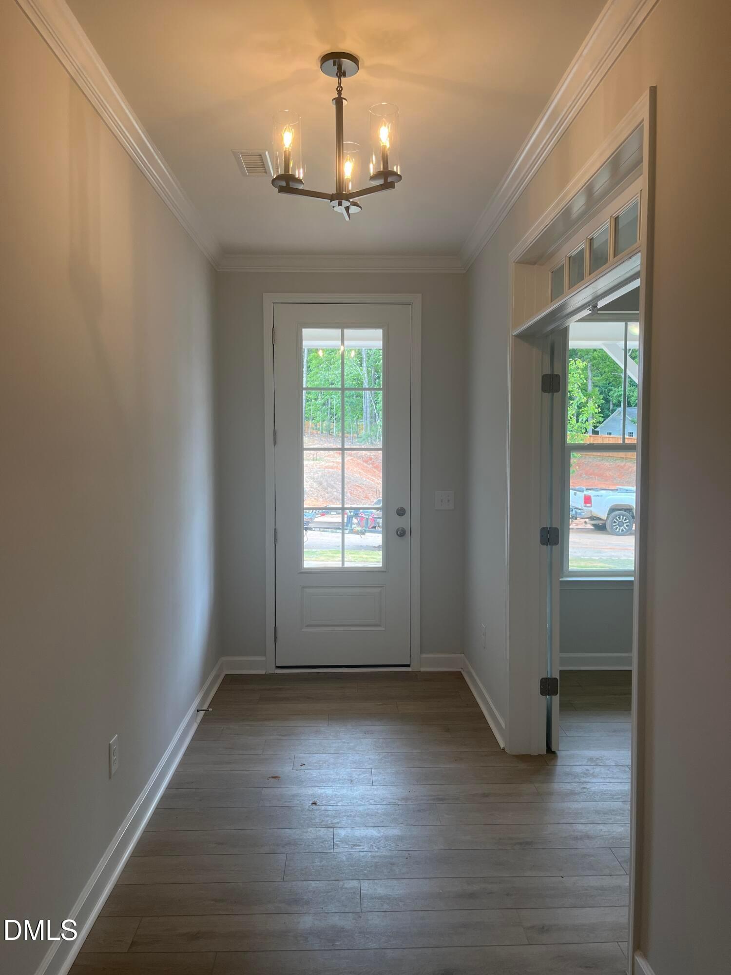 Bright entryway with hardwood floors, chandelier, and glass-paneled door in Davidson Homes The Birch II E, Wake Forest, NC