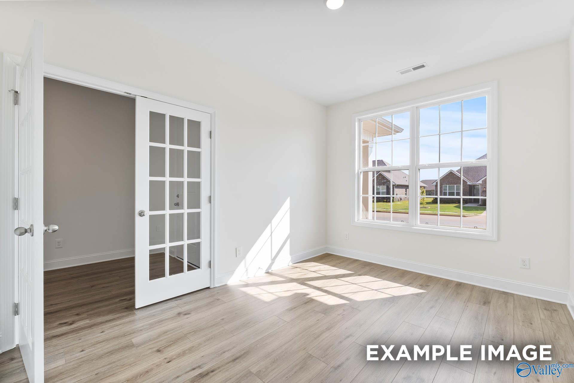 Bright home office with French doors and wood-look flooring in The Harrison floor plan at River Road Estates, Decatur.