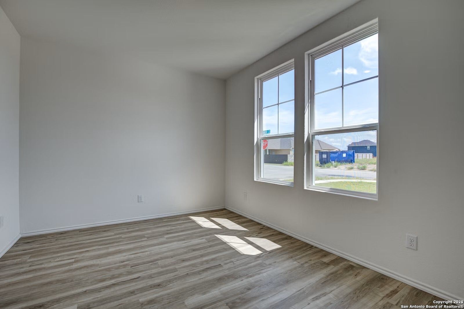 Bright empty bedroom with luxury vinyl plank flooring and large sunny windows in Davidson Homes The Douglas B, Seguin, Texas