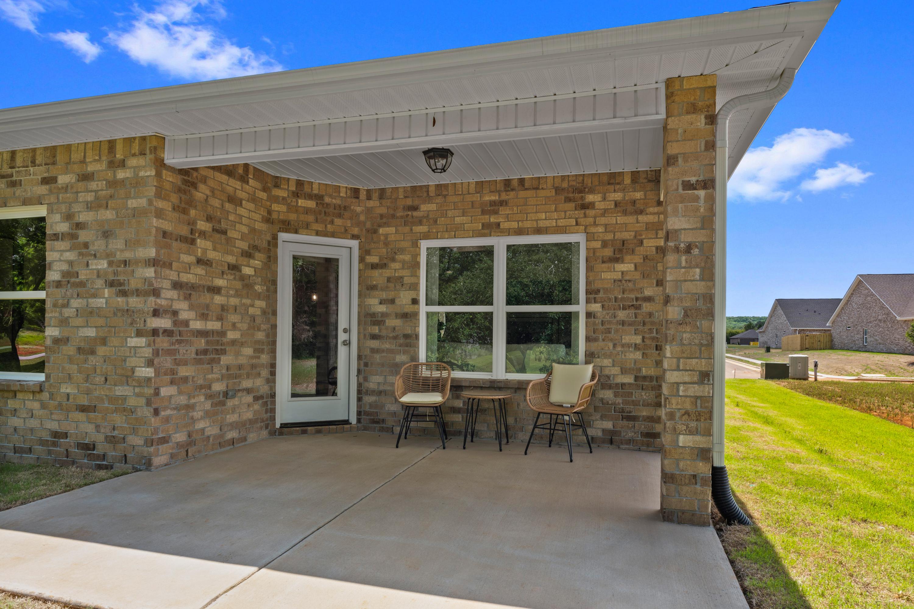 Brick home covered porch at Hollon Meadow in Decatur Alabama with wicker seating green lawn and blue sky
