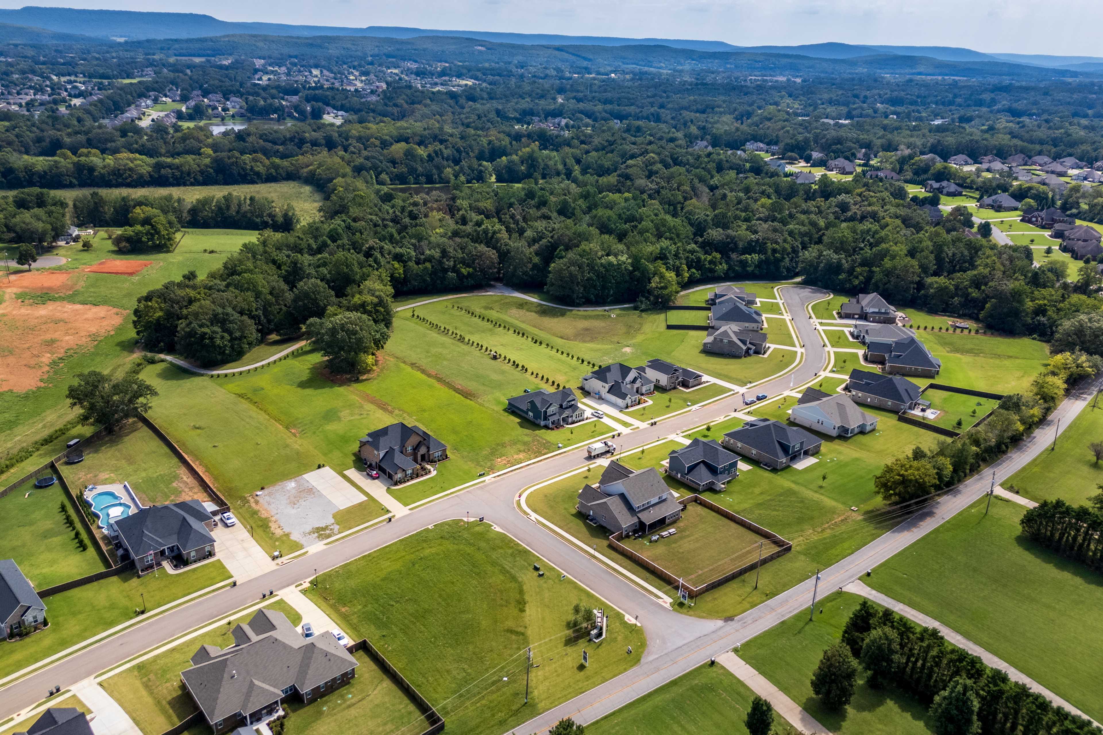 Aerial view of Riverton Preserve neighborhood in Huntsville Alabama with modern Davidson Homes, green lawns, pool, and wooded surroundings