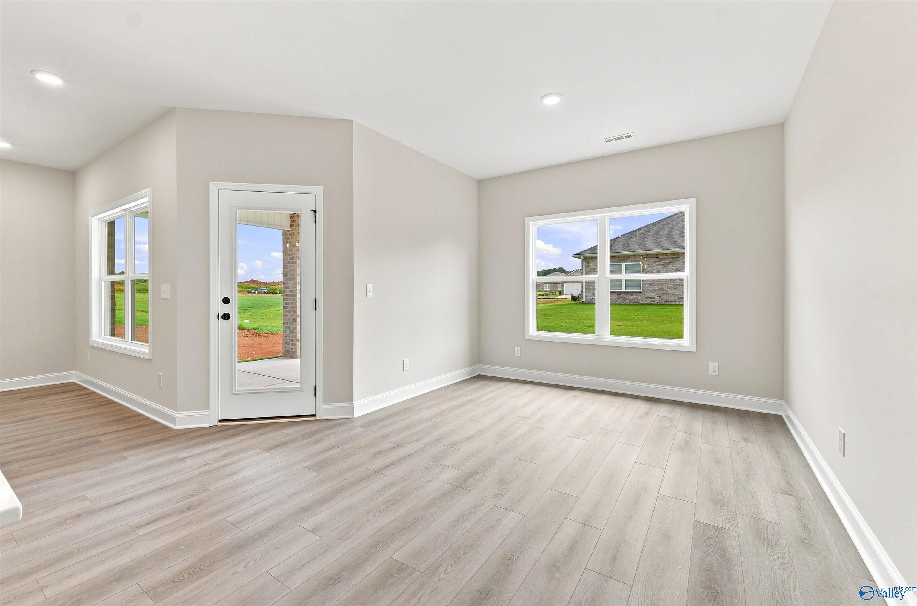 Bright open-concept living area with luxury vinyl plank floors and glass back door in Davidson Homes Everett B, Toney, Alabama