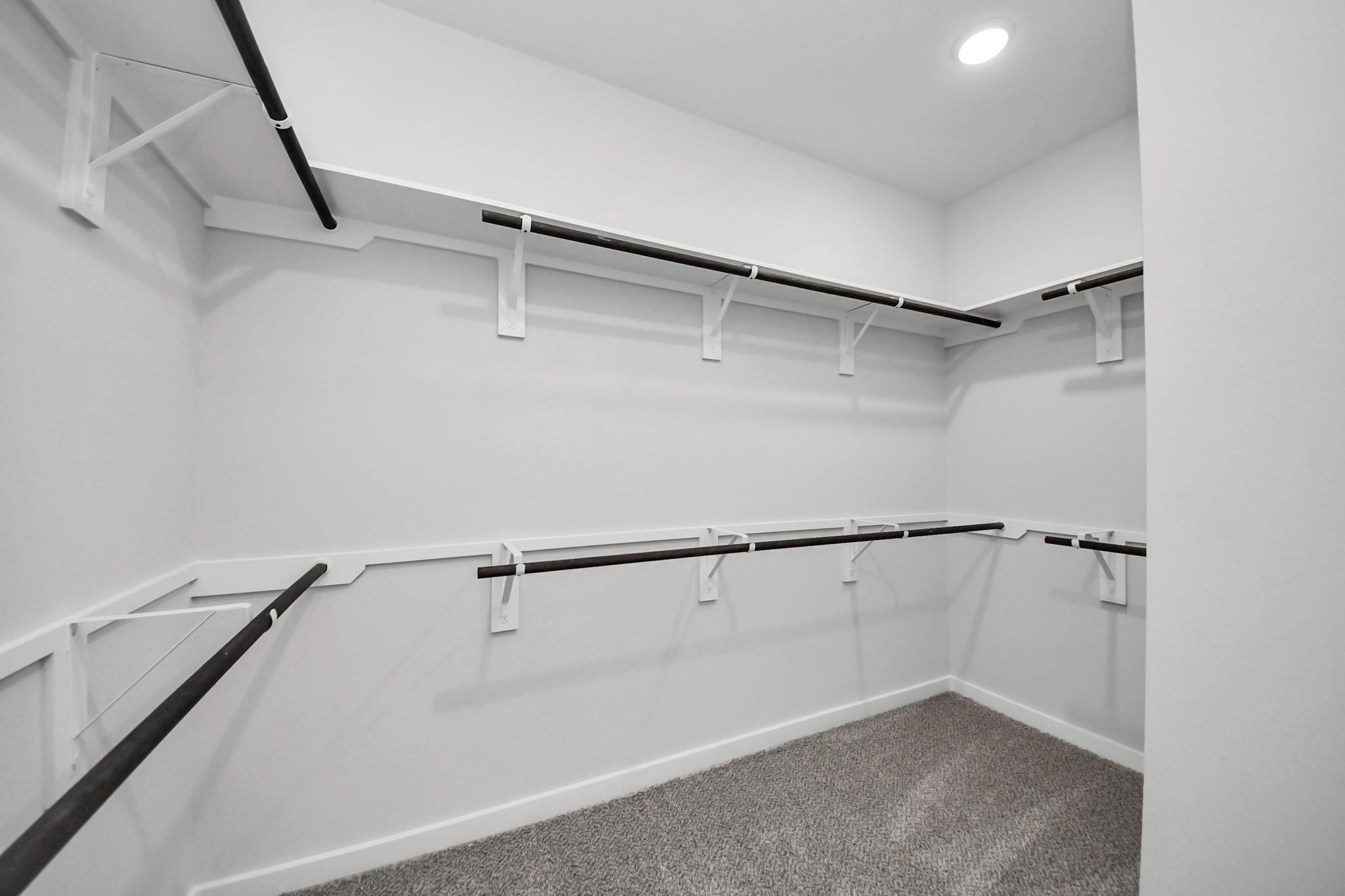Spacious walk-in closet with custom shelving in The Riviera C floor plan at River Ranch Meadows, Dayton, Texas.