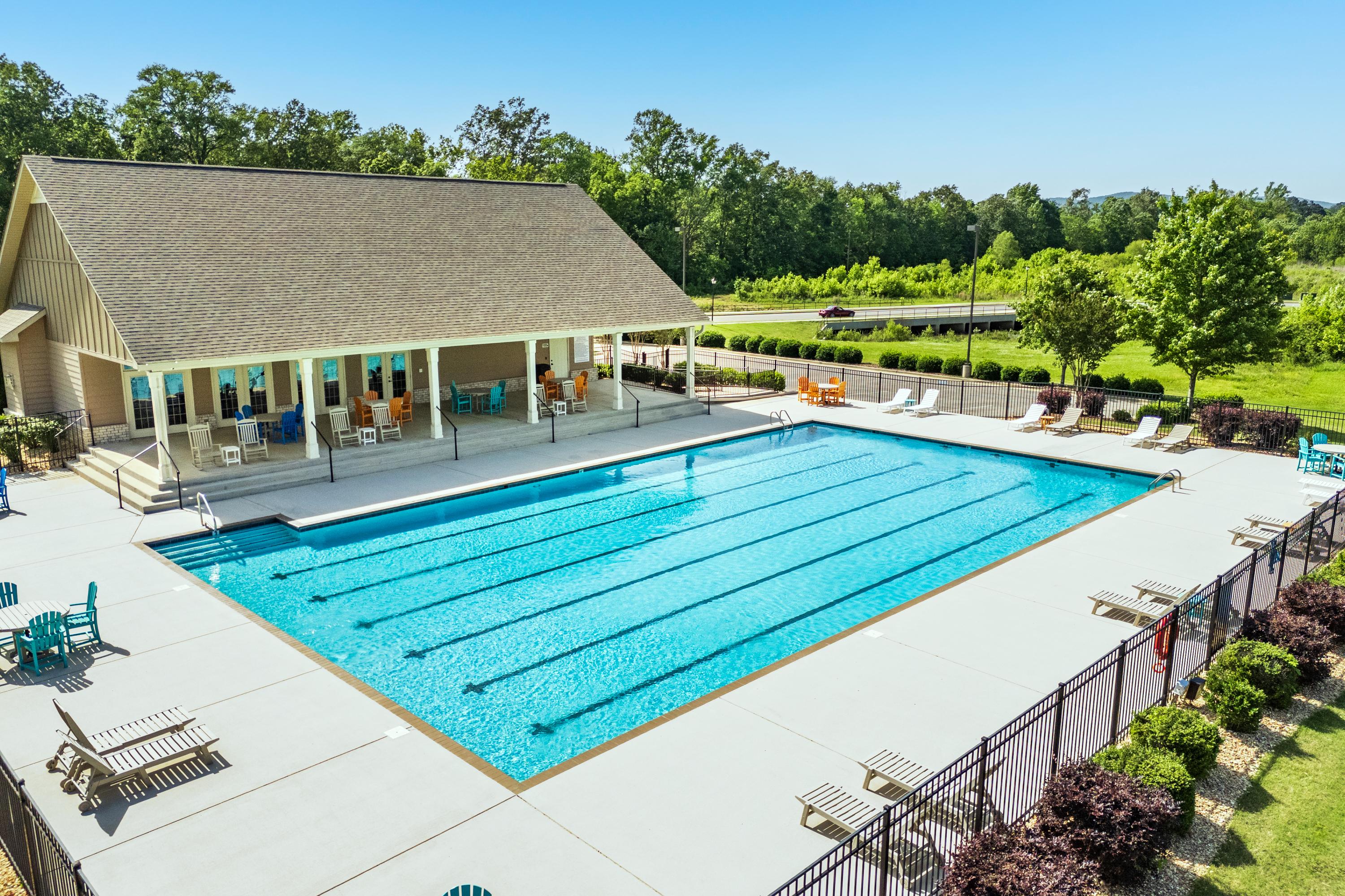Resort-style lap pool at The Meadows at Hampton Cove in Owens Cross Roads Alabama with lounge chairs, umbrellas and covered clubhouse