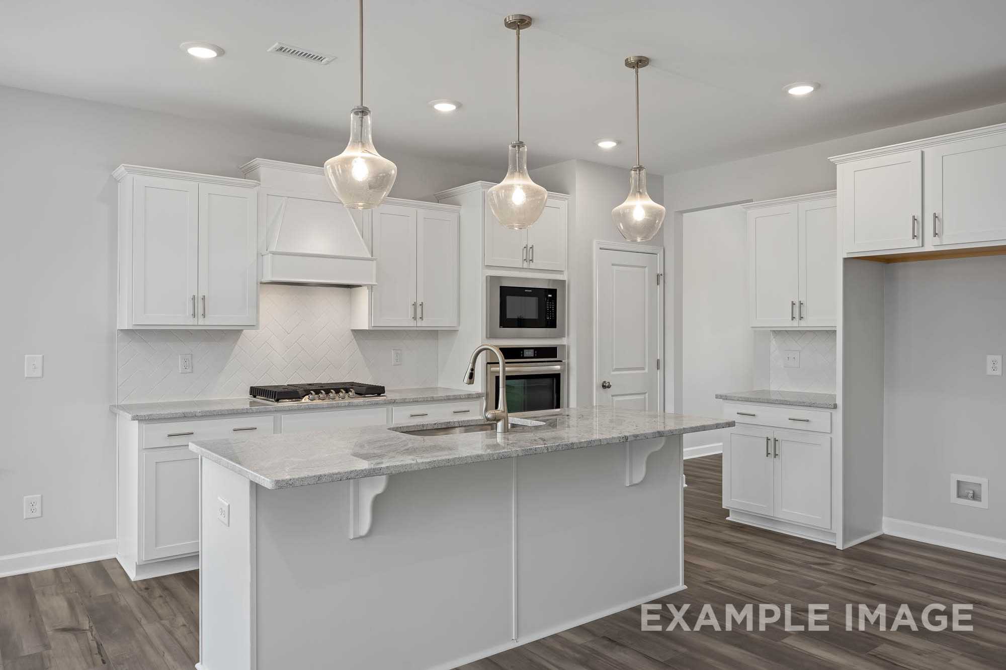 Spacious gourmet kitchen in The Ash by Davidson Homes featuring white shaker cabinets, quartz island, and pendant lighting