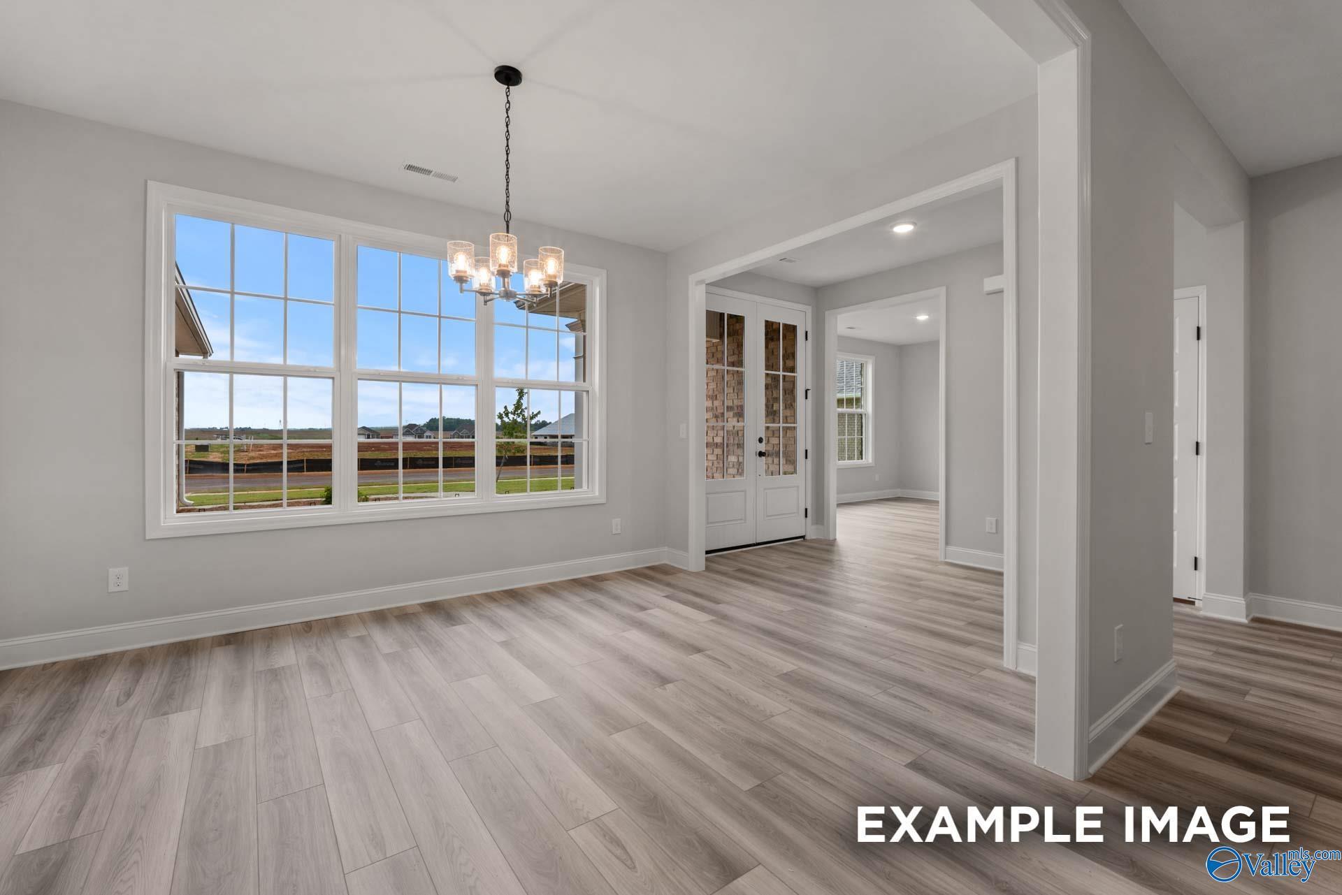 Bright dining room with large windows overlooking field, chandelier, light wood floors in The Finleigh home, Meridianville, Alabama