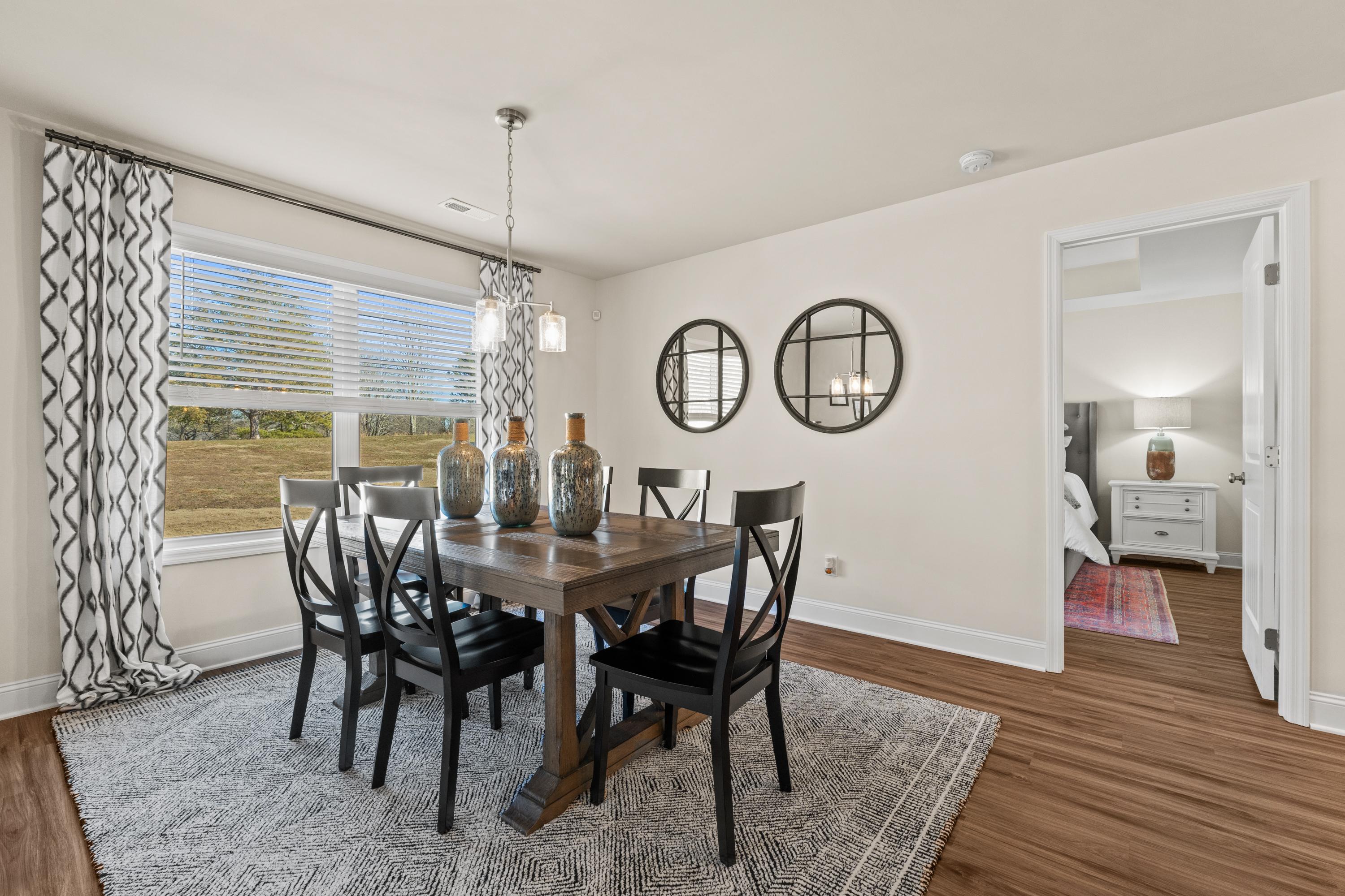 Dining room in Berry Cove, New Market Alabama with rustic wooden table, black chairs, pendant light, and scenic field view through large window