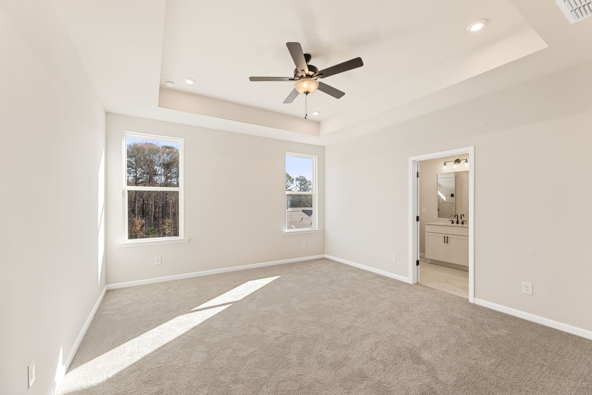 Bright bedroom with large windows, ceiling fan, neutral walls, and en-suite bath in Davidson Homes The Glenwood C, Loganville, GA