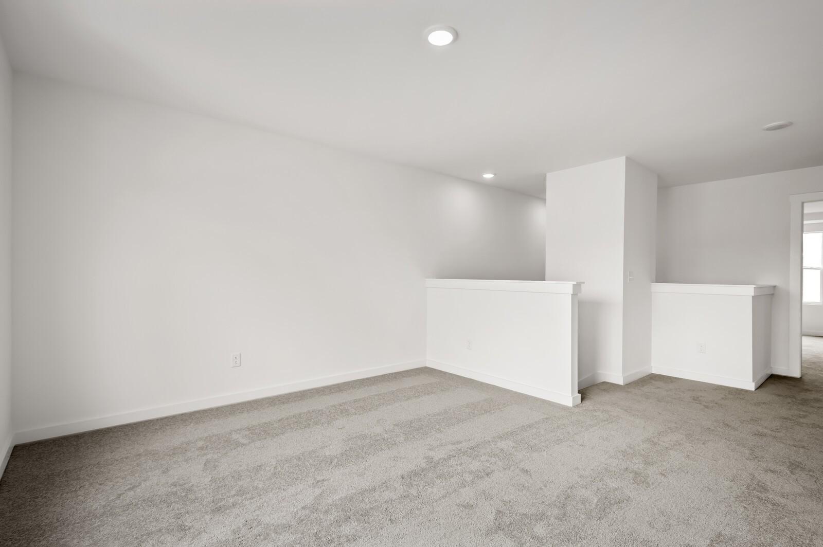 Spacious upstairs loft area with neutral carpet in The Logan C floor plan by Davidson Homes in Calista Farms.