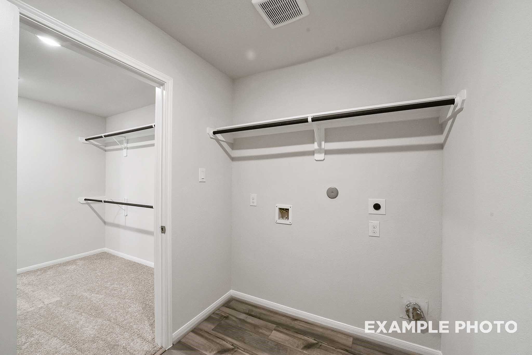 Bright laundry room with built-in shelves, hanging rods, utility sink in Davidson Homes Tierra B, Beasley, Texas