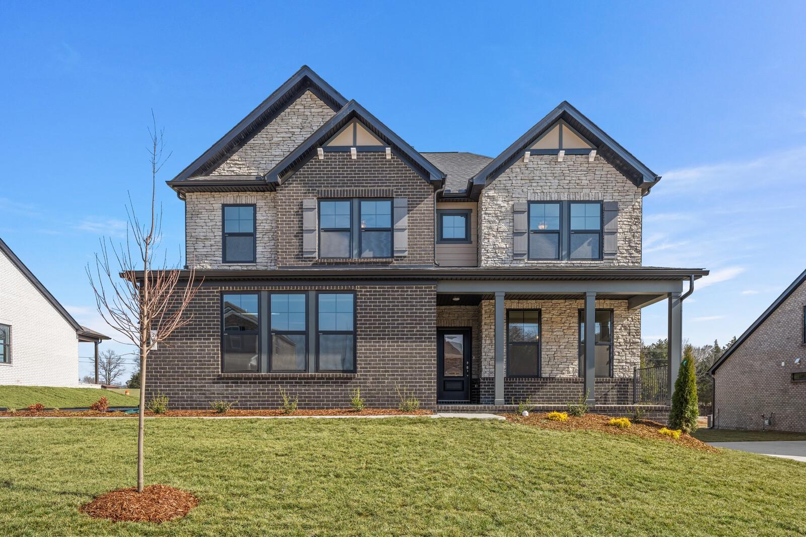Two-story brick and stone home with black shutters, front porch, and lush lawn in Benders Cove, Mt. Juliet, Tennessee