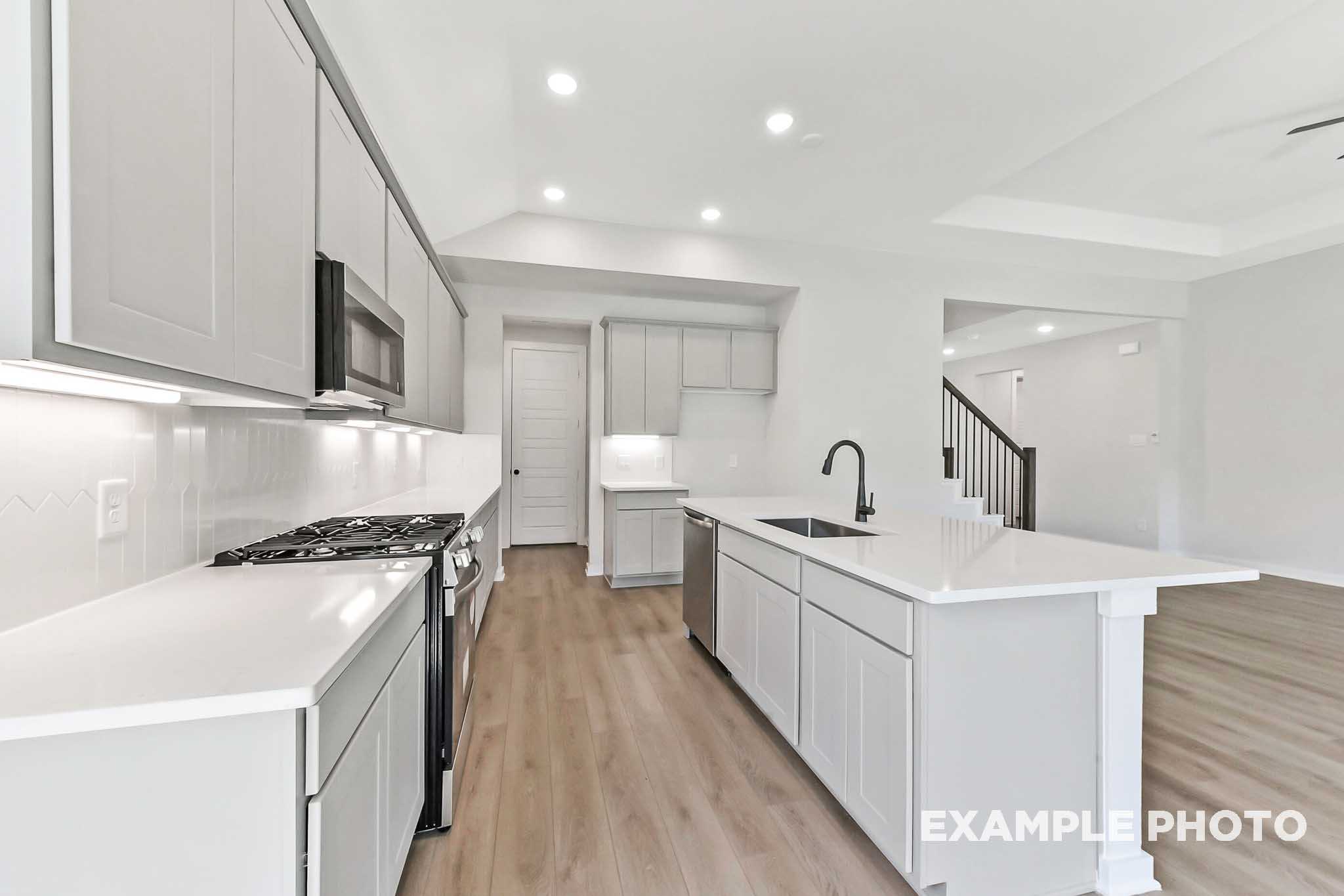 Spacious modern kitchen in The Sequoia Davidson Homes featuring white cabinetry, large quartz island, and open-concept living area